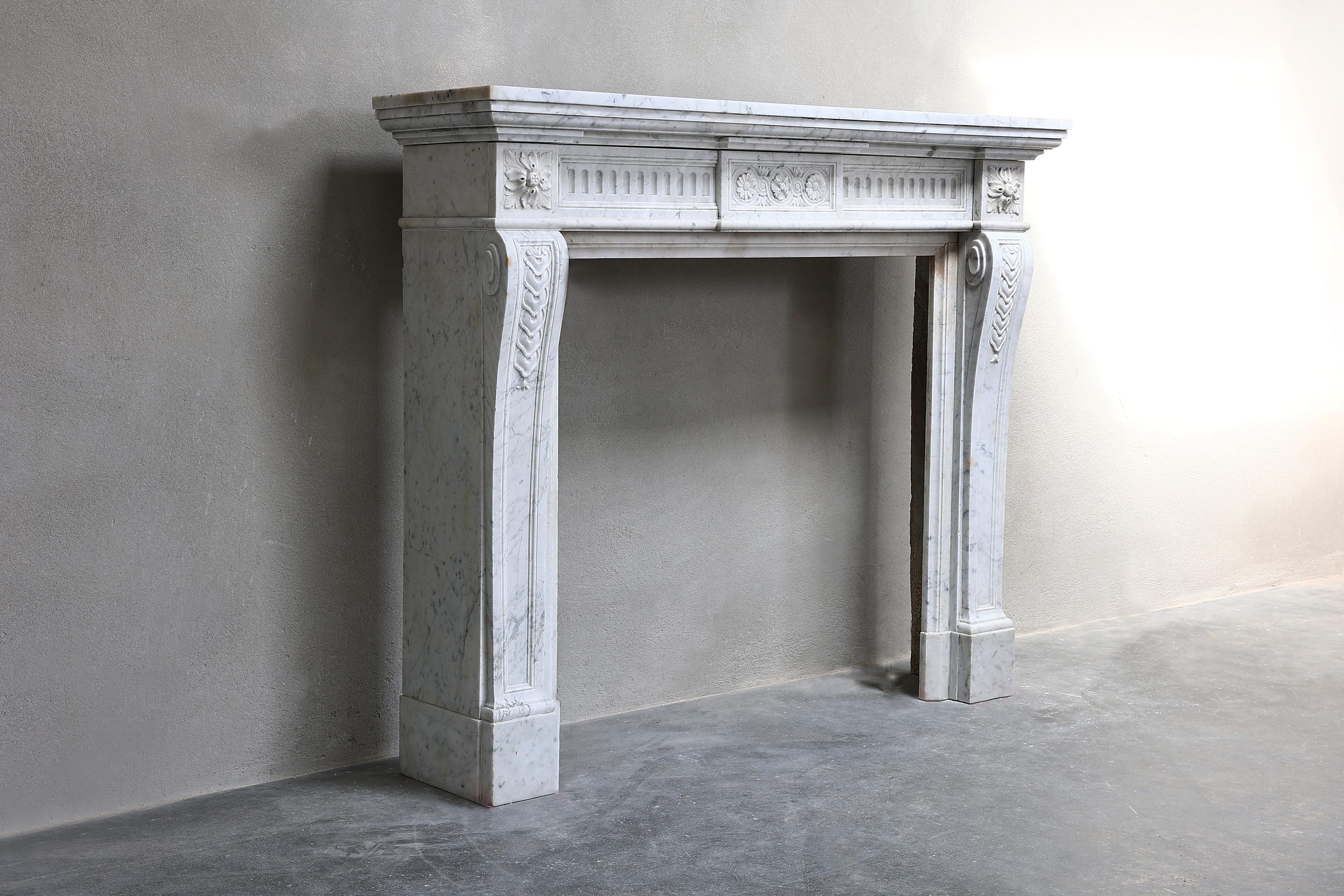 Beautiful 19th century Carrara marble fireplace in the style of Louis XVI. This antique fireplace has straight shapes and beautiful ornaments in the front part and on the legs. This charming fireplace has a compact size and chic look.