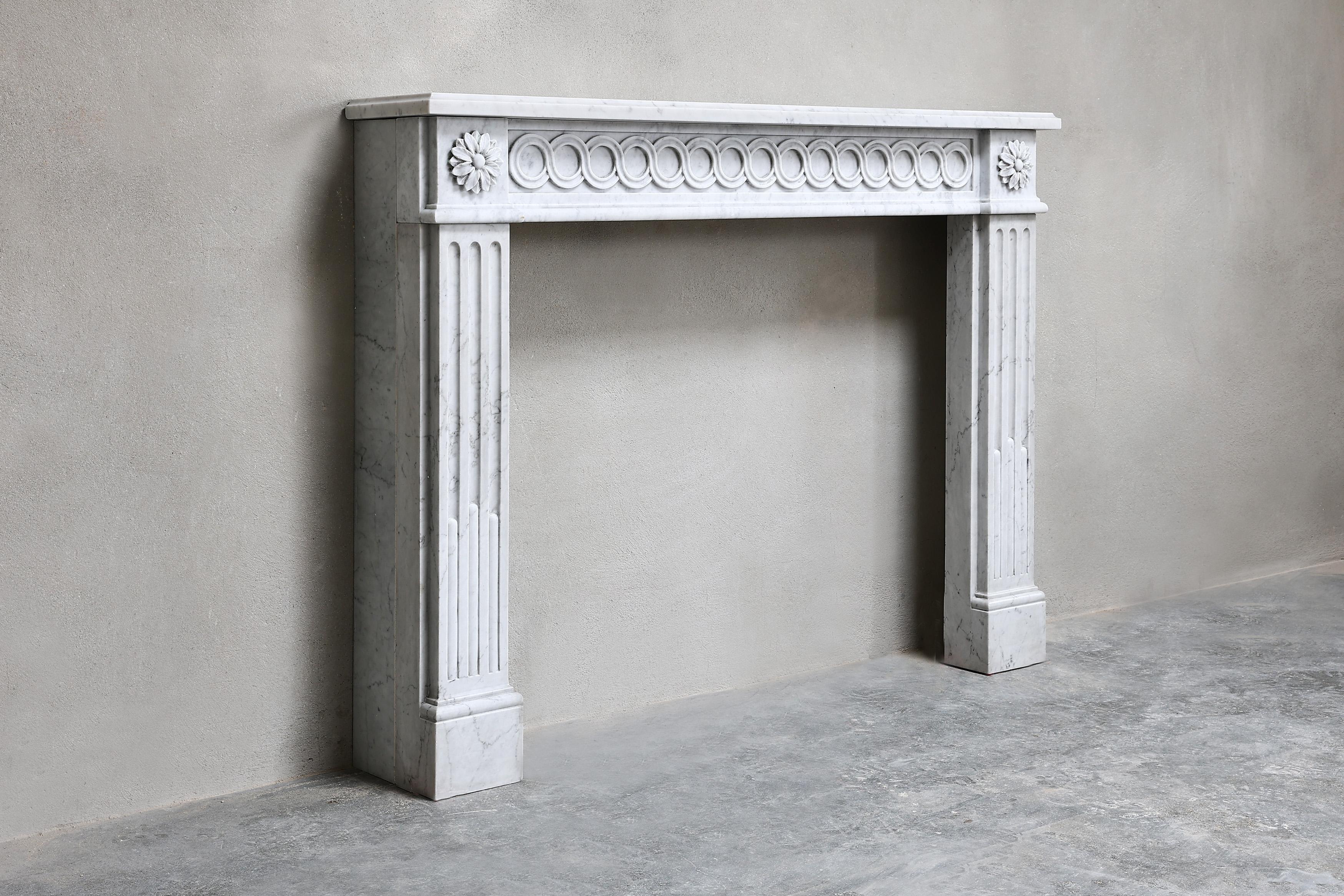 Beautiful compact antique fireplace made of Carrara marble from Italy in style of Louis XVI. This fireplace from the 19th century has straight shapes and elegant ornaments, making the fireplace graceful! An asset to many interiors.