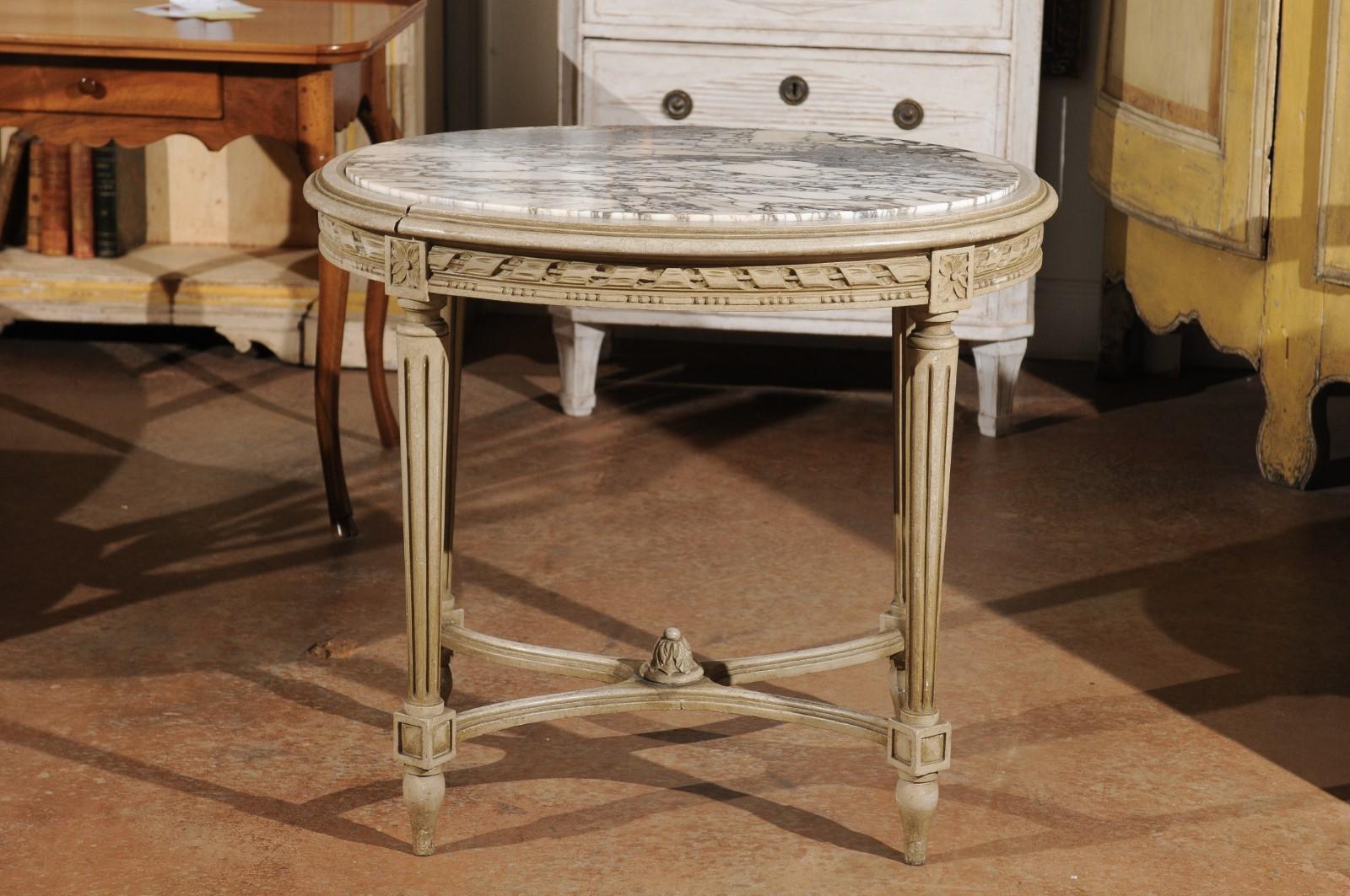 A French Louis XVI style oval accent table from the late 19th century, with marble top, twisted ribbon motifs, fluted legs and X-form cross stretcher. Born in the later years of the 19th century during the Belle-Époque era, this French accent table