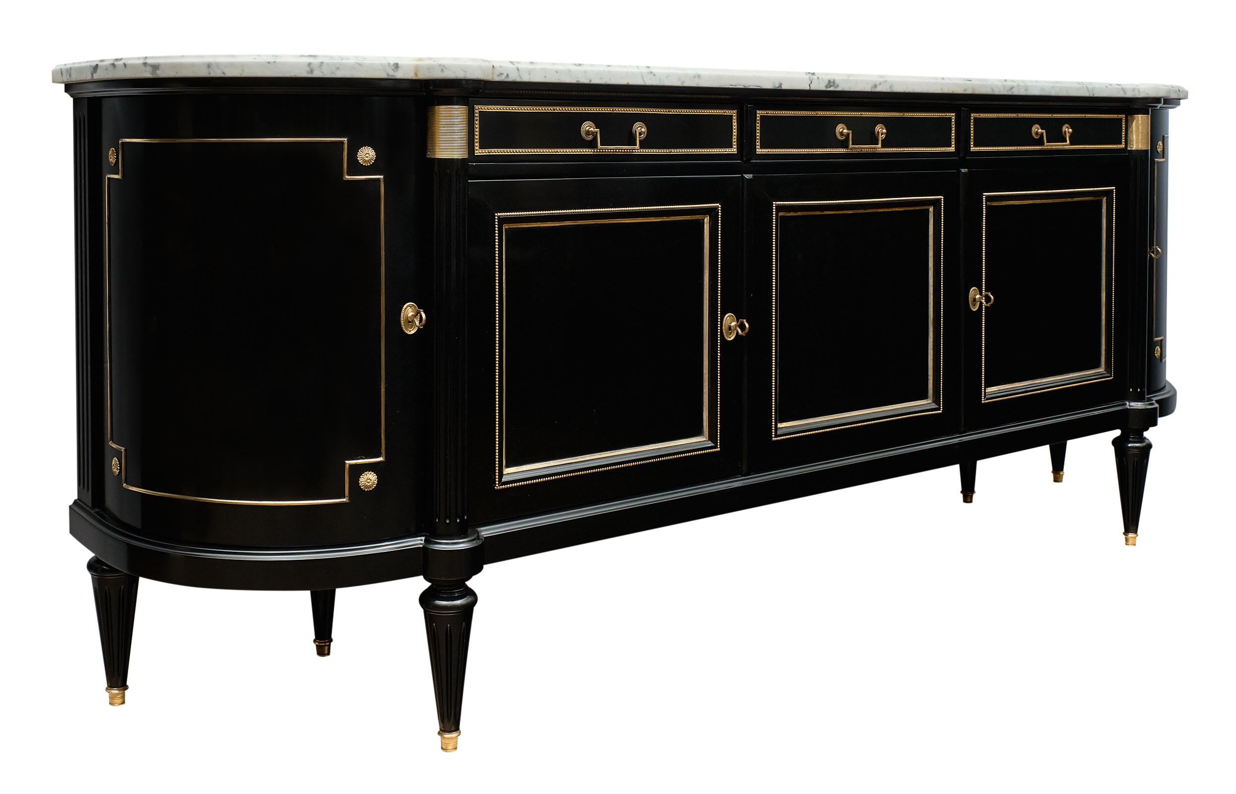 Louis XVI style French antique curved buffet made of mahogany that has a lustrous; Museum quality ebonized French polish finish. The gilt brass trim and hardware throughout contrasts strikingly with the black color and makes an impressive showing.