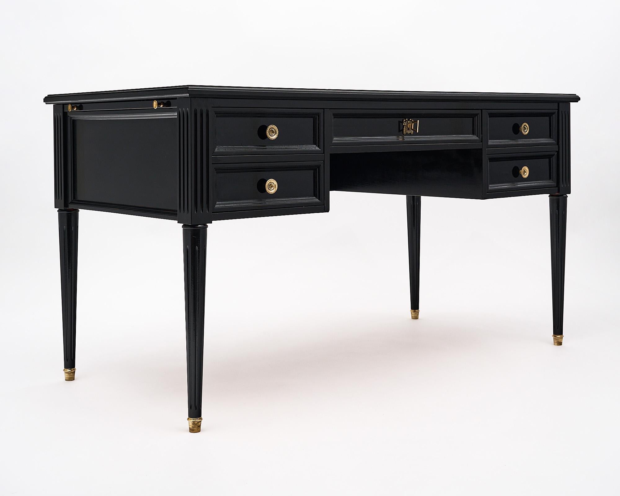 Desk, French, in the Louis XVI style. This piece is made of mahogany that has been ebonized and finished in a lustrous museum quality French polish. There are five drawers with replacement bronze hardware. We love the fluted, tapered legs. The