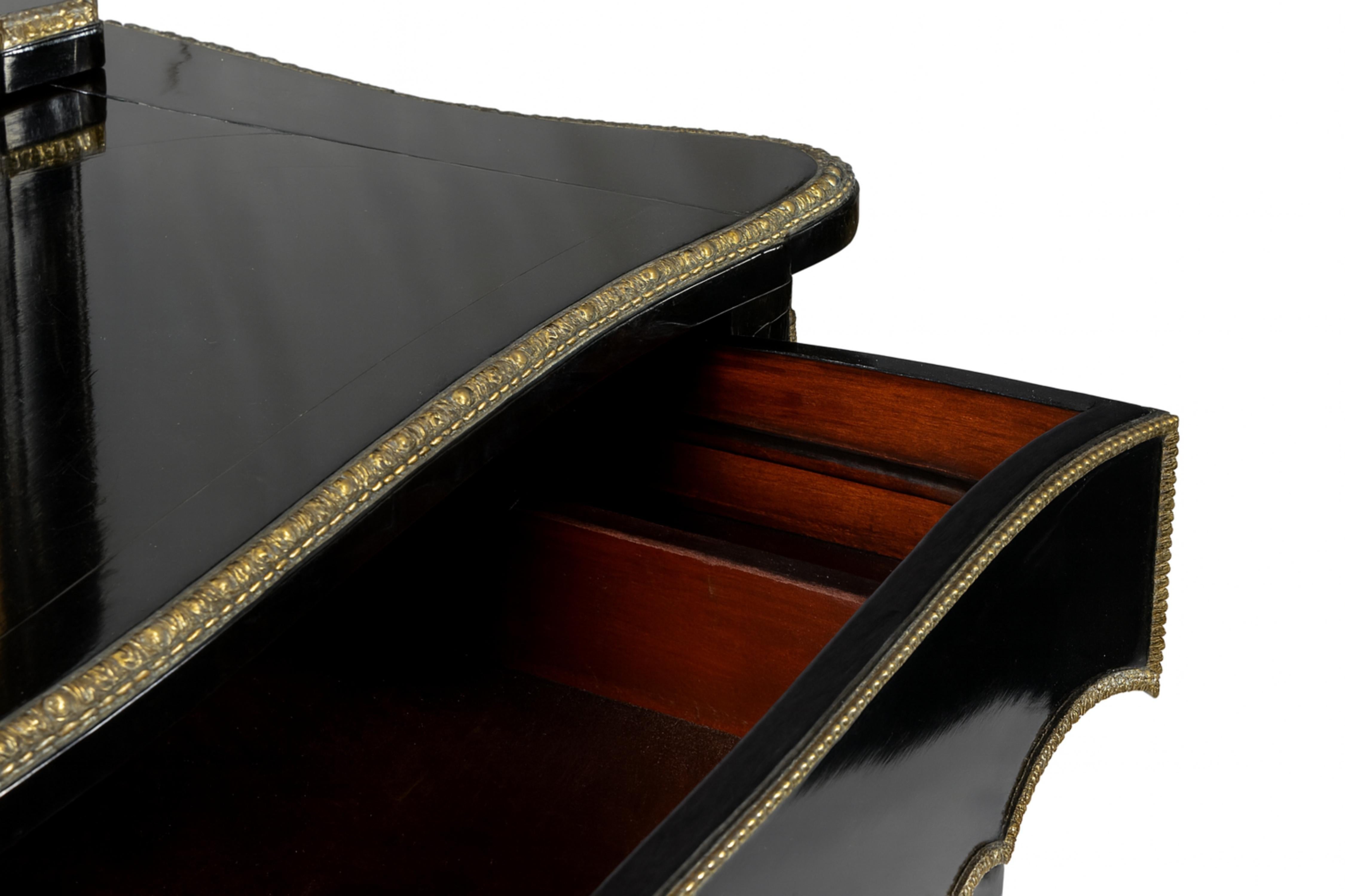 Un raro Bonheur Du Jour rifinito in lacca nera con montature in ottone dorato.
Un pezzo in stile Eleg XVI della fine del XIX secolo con quattro cassetti superiori e un grande cassetto inferiore con guide dorate sollevate su eleganti gambe