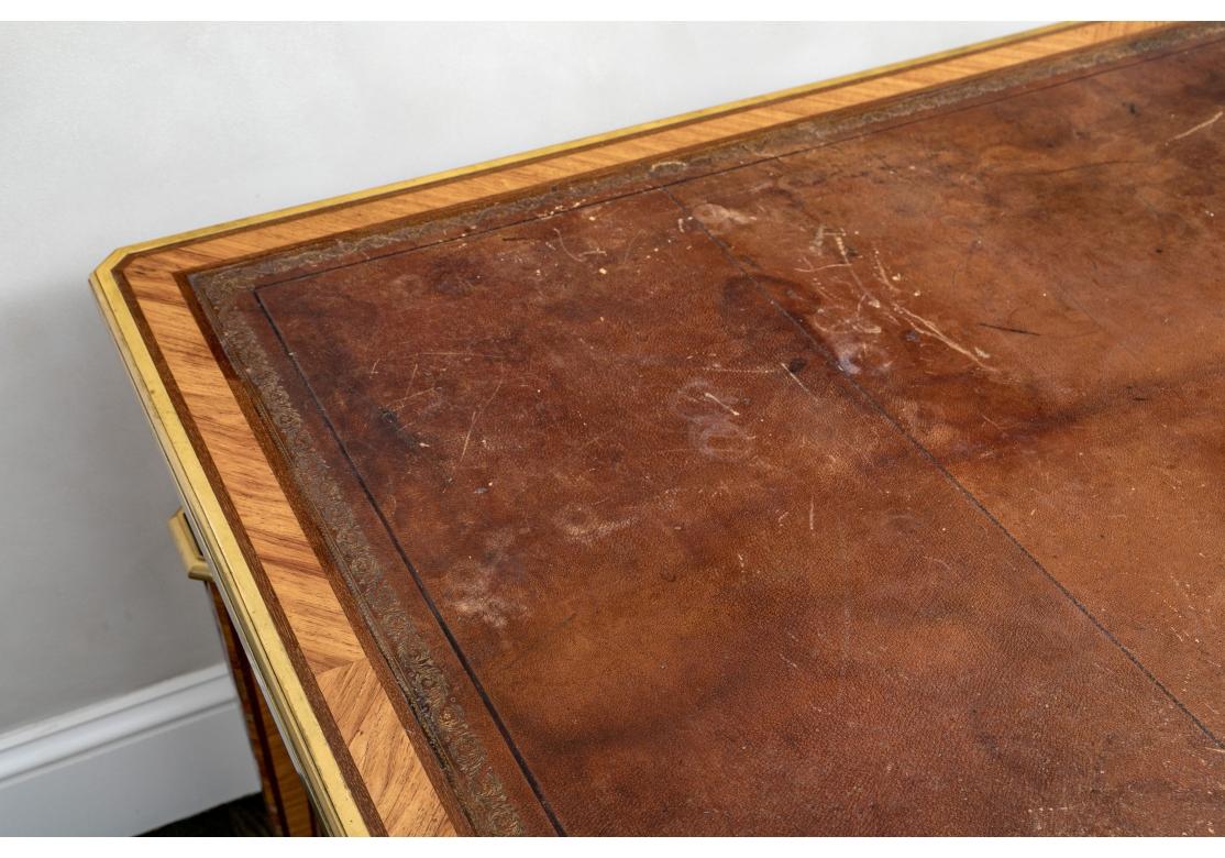 Bureau de style Louis XVI en acajou, bois de satin et bois de chêne.  Marqueterie de noyer français avec bandes de bronze. Le bureau est à double face, avec un plateau en cuir d'origine, des écussons et des montures en bronze, et repose sur des