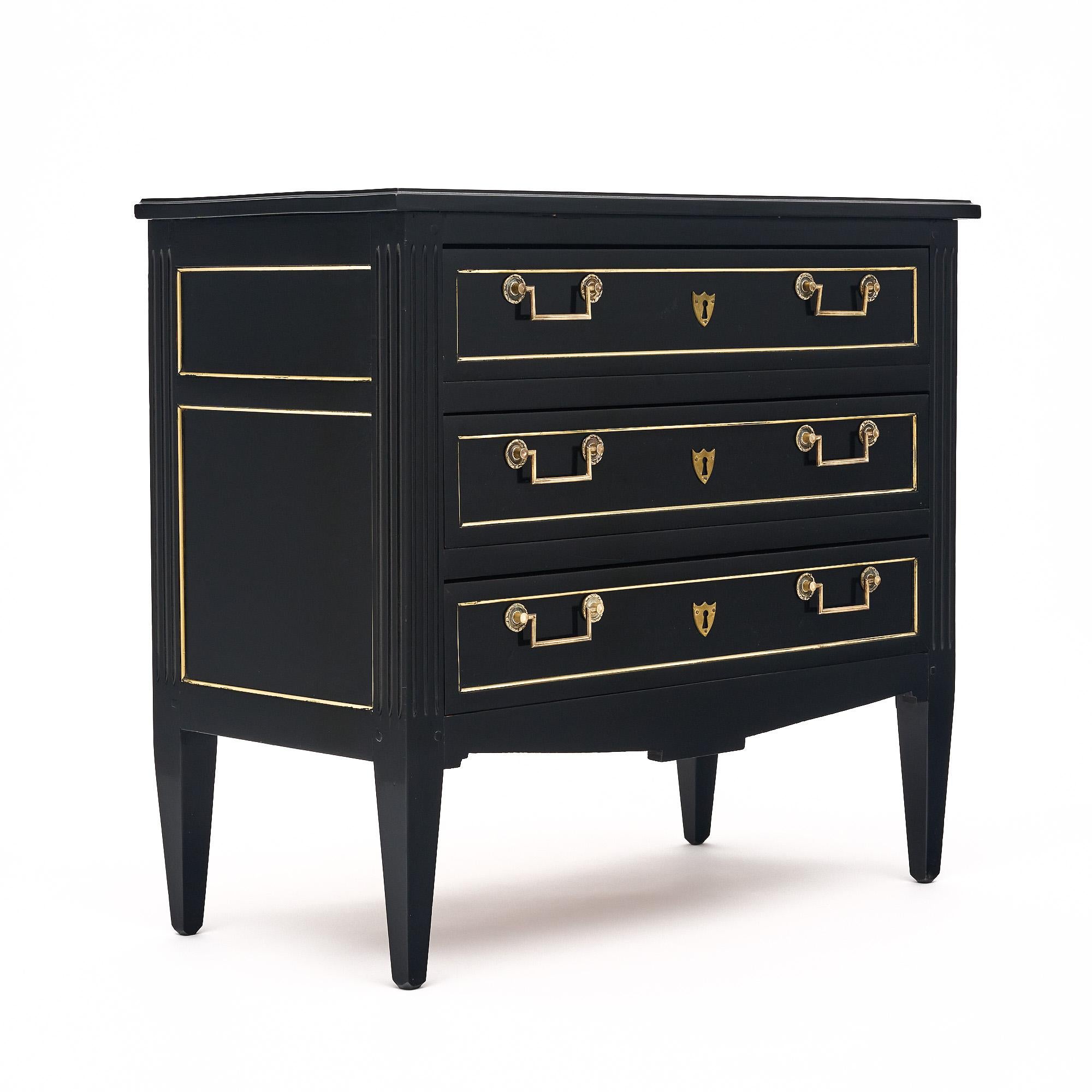 Chest of drawers, French, in the Louis XVI style made of mahogany. This piece has three dovetailed drawers, gilt brass pulls and trim throughout. The petite commode boasts a lustrous Museum quality ebonized French polish.
