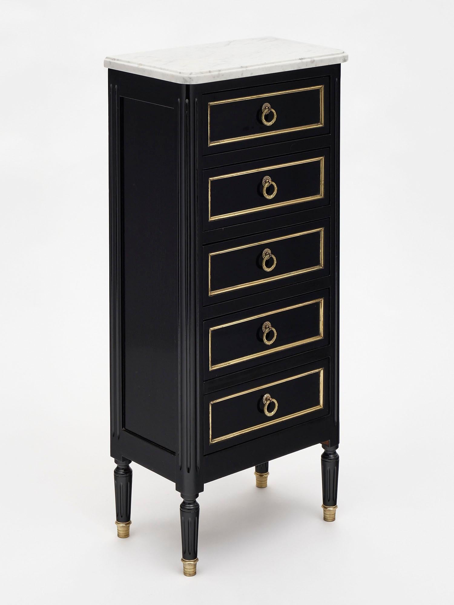 Louis XVI style French chiffonier made of mahogany that has been ebonized and finished with a lustrous French polish. There are five dovetailed drawers each trimmed in gilt brass and featuring bronze hardware pulls. The feet are also capped with