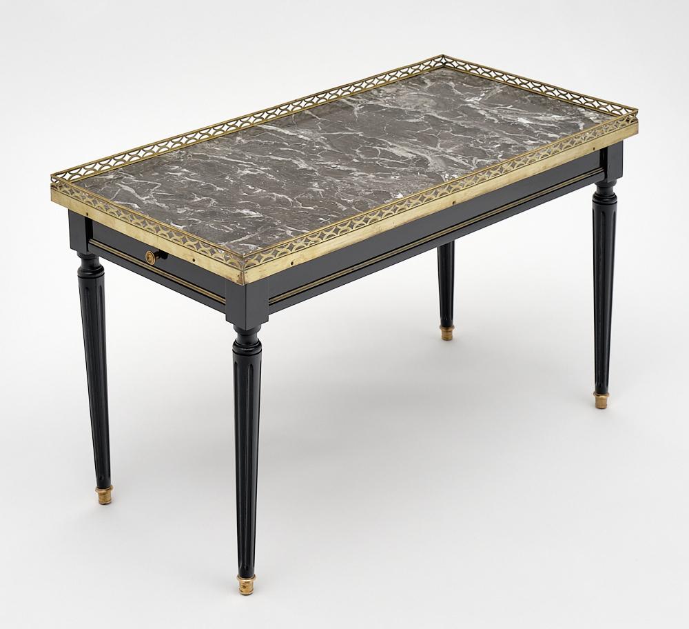 Louis XVI style French coffee table made of solid mahogany that has been finished in a lustrous ebonized French polish. We love the gilt brass trim throughout and the Classic lines of this piece. It is topped by an original; intact Sainte Anne