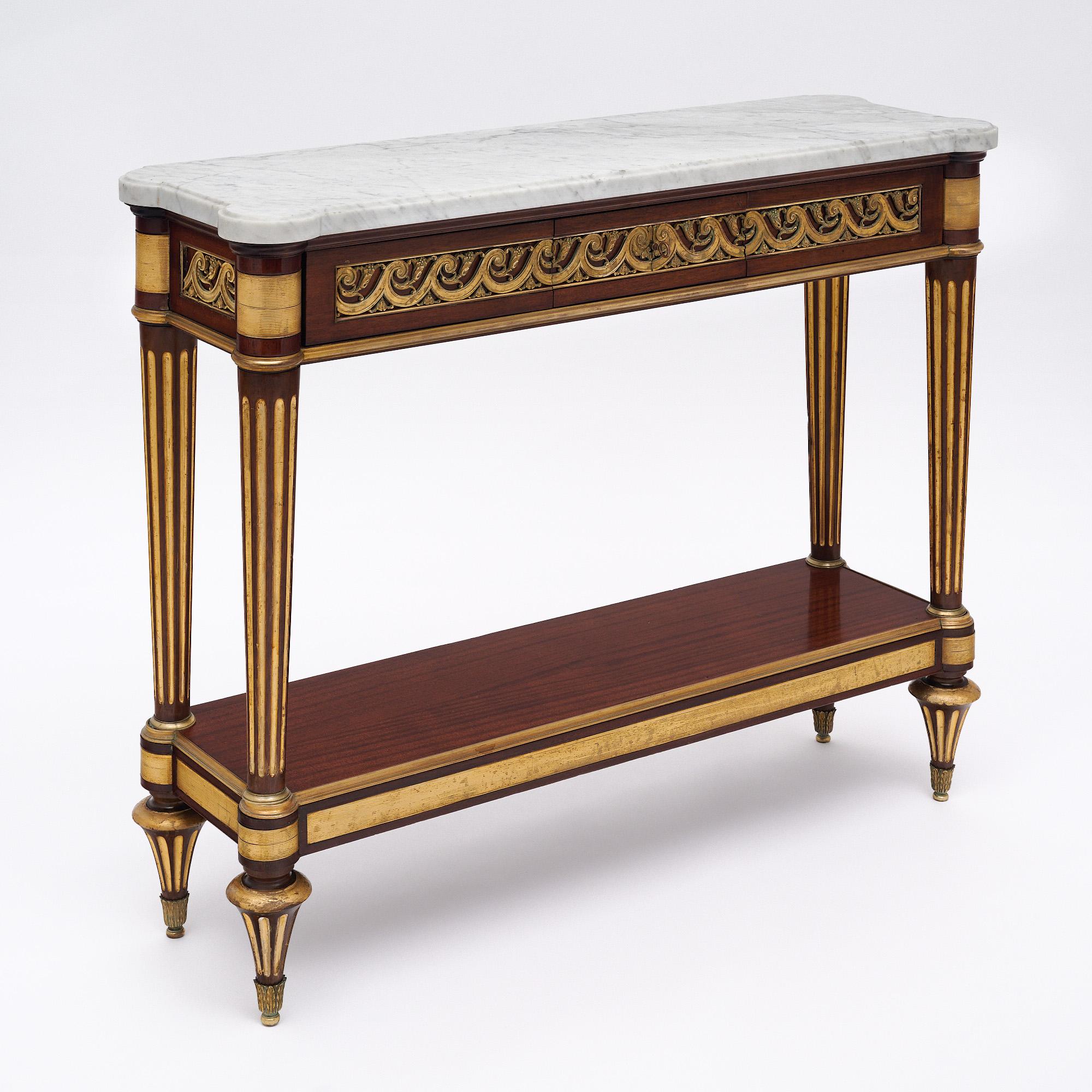 Console table from France in the Louis XVI style. This piece is made of mahogany with striking hand-crafted detail throughout. There is one dovetailed drawer and a lower shelf for functionality. It is supported by fluted legs. There is gold-leafing