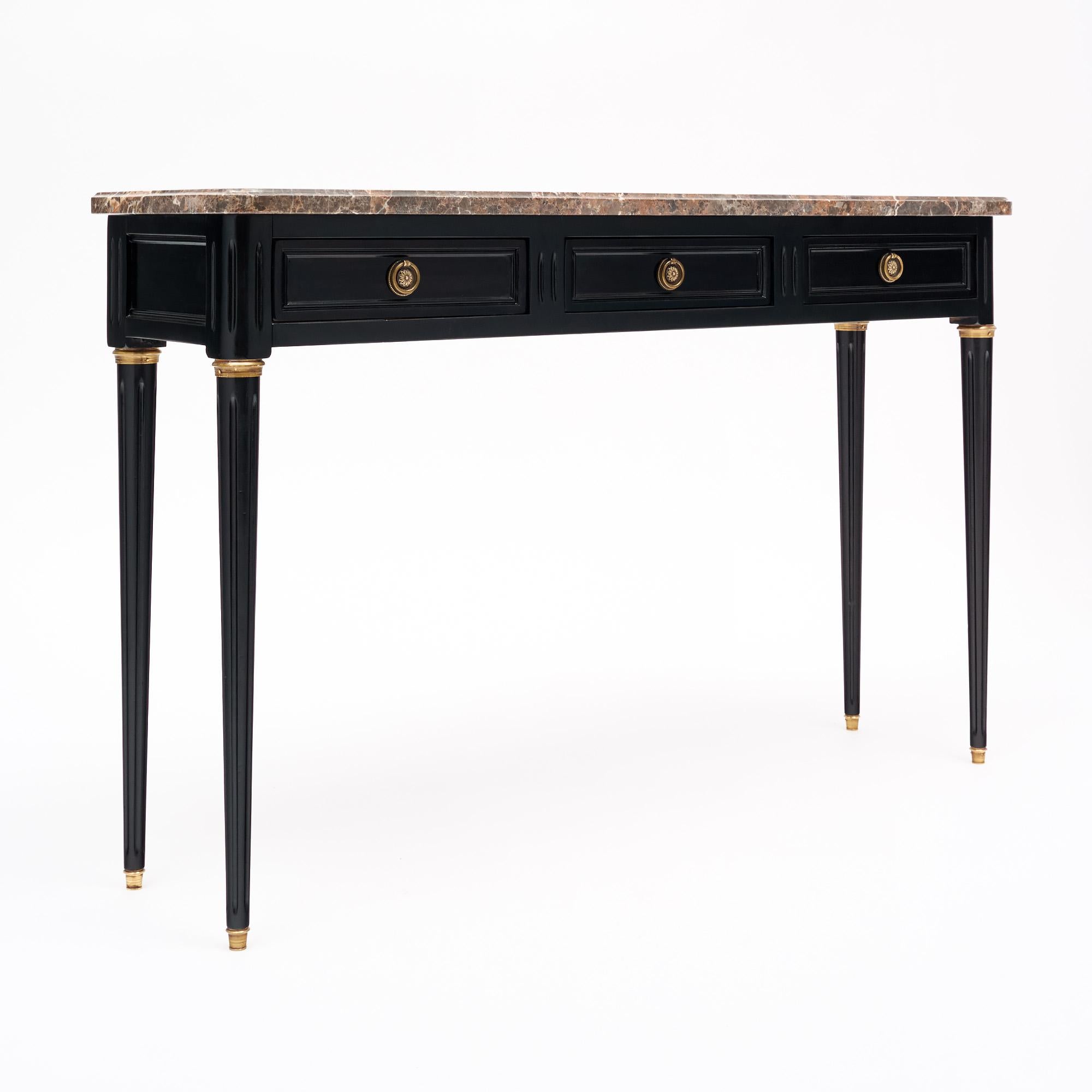 Table console de France de style Louis XVI. Cette pièce est fabriquée en bois massif, principalement en acajou. Elle est ébonisée et a été finie avec un vernis français lustré de qualité muséale. Il y a trois tiroirs à queue d'aronde, chacun avec