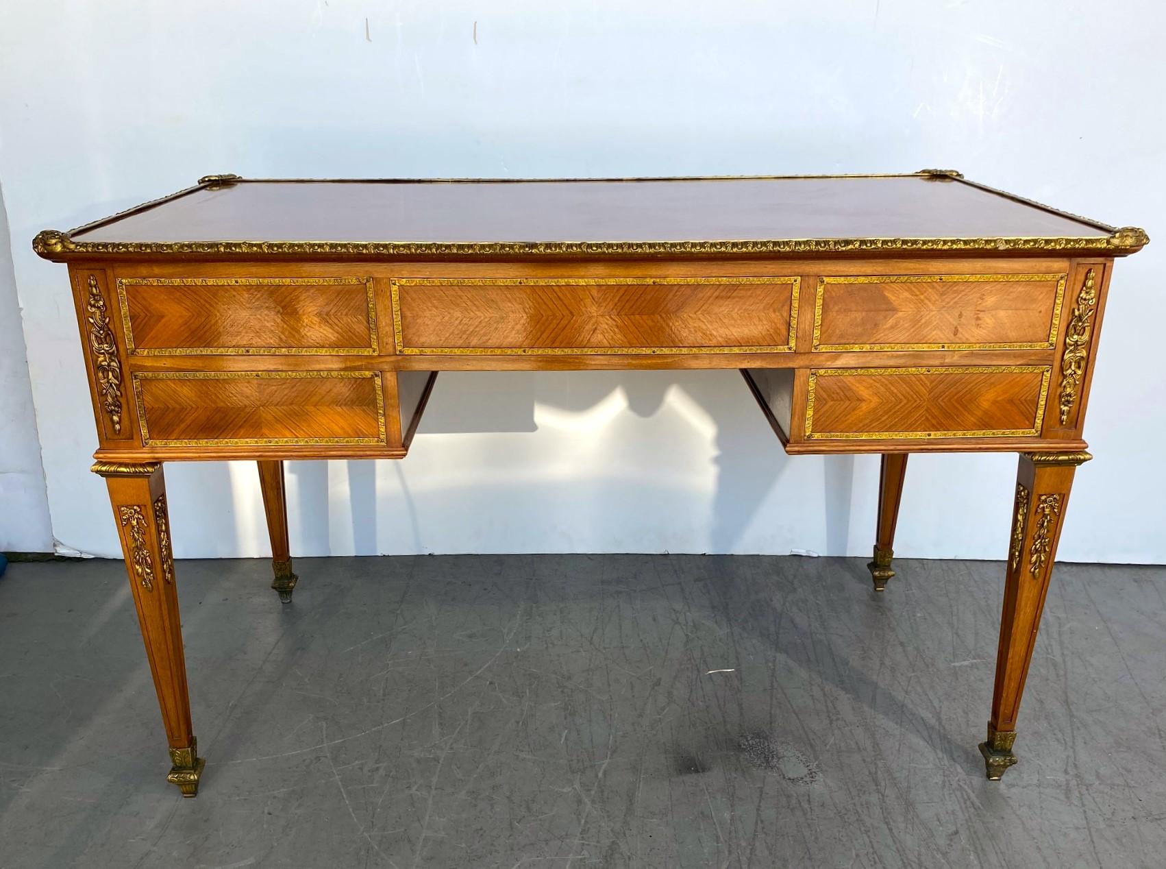 Pregevole scrittoio francese in noce e mogano ornato di ormolu, in stile Luigi XVI, caratterizzato da un motivo a intarsio di mogano, con finiture in ottone intorno al bordo, con cinque cassetti con finiture in ottone intorno al buco della serratura