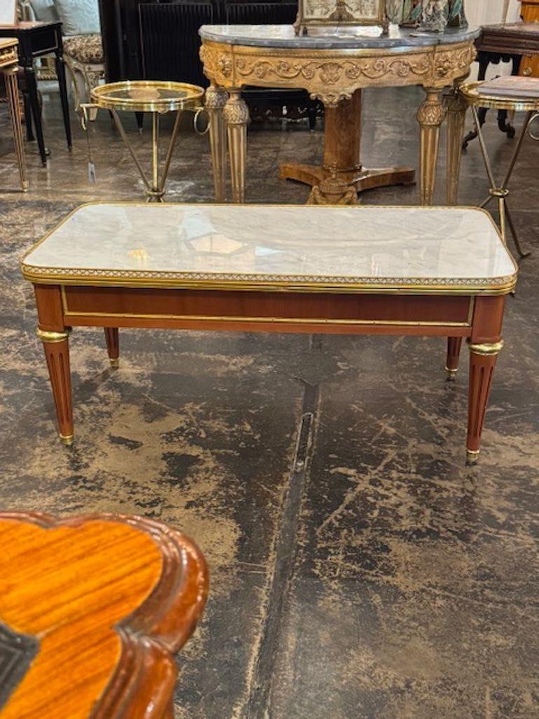 Belle table basse en acajou et marbre de style Louis XVI. Elle présente une belle finition en bois, des détails dorés et une bordure de galerie en laiton. Un vrai classique ! Circa 1940.
44w x 22d x 20h