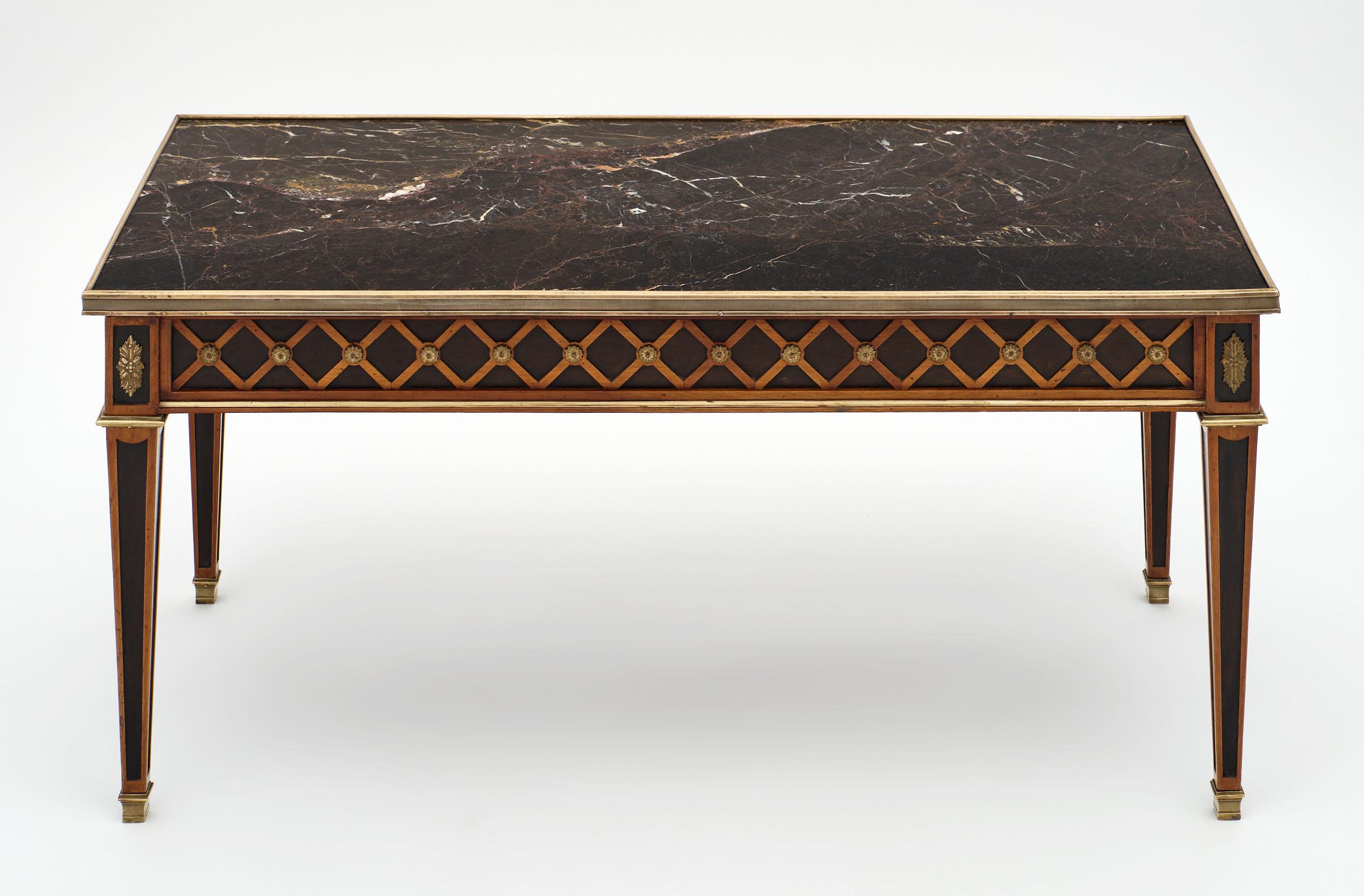 French Louis XVI style marble-topped coffee table made of solid cherrywood and topped with a “portoro” intact marble slab. The gilt brass trim and rosace add beautiful detail throughout. We loved the neoclassical frieze and the finesse of the cast