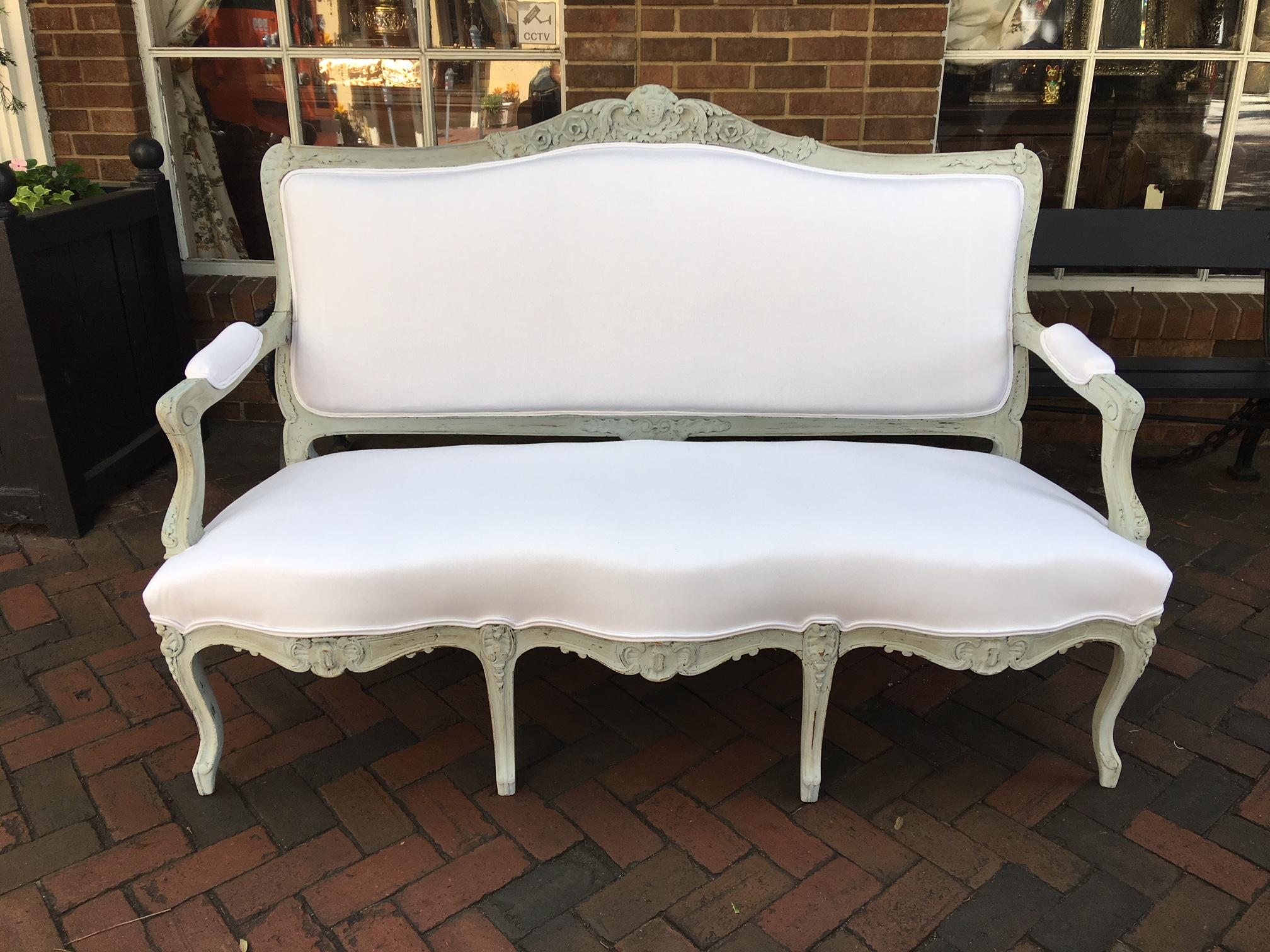 Louis XVI style French painted wood upholstered settee or sofa with carved floral decorations, 19th century.