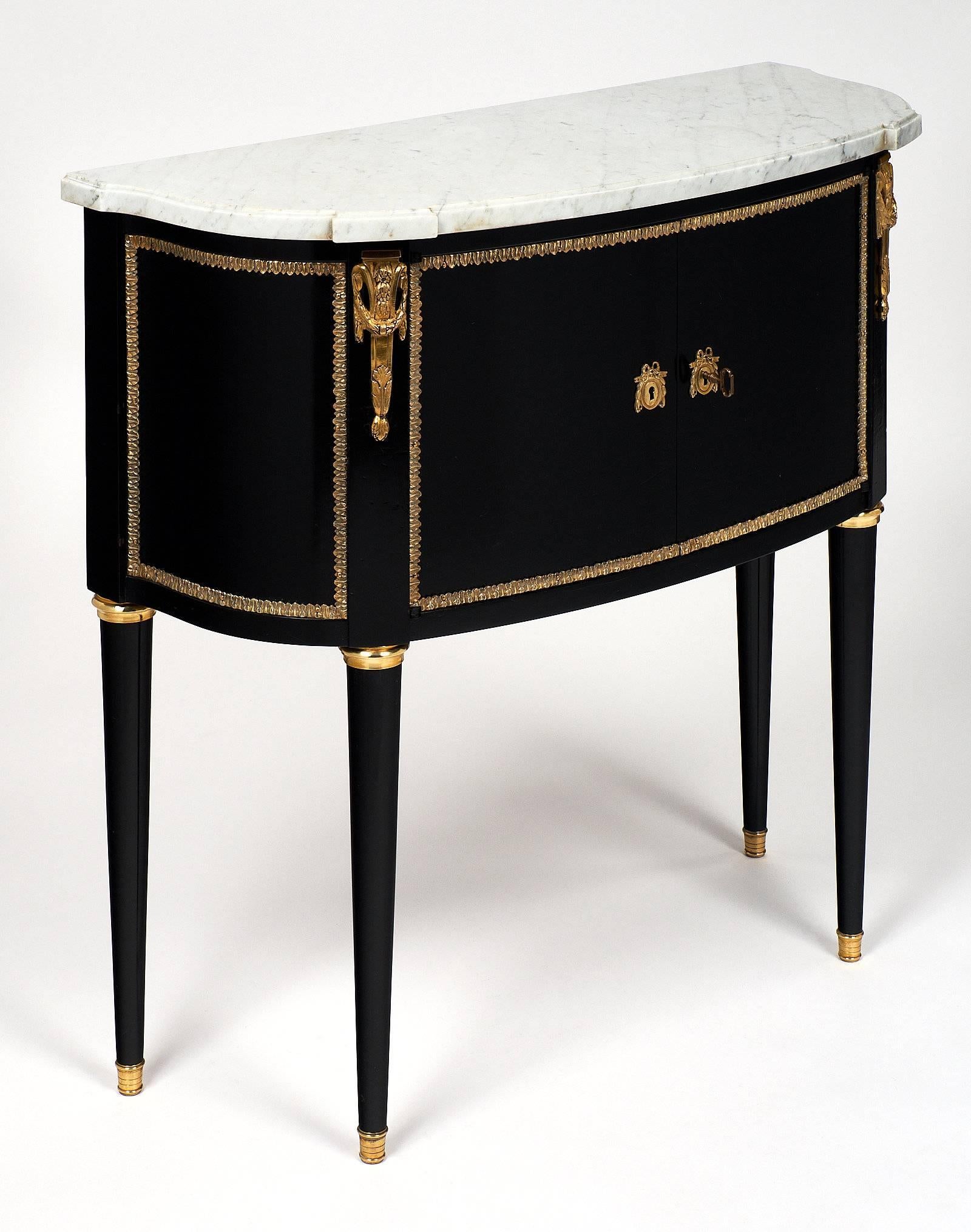 A charming “Serpentine“ buffet finished with a museum quality lustrous French polish and featuring an intact Carrara marble top. It has slightly curved front doors and sides, fluted legs, gilt brass trim throughout, and finely cast hardware and