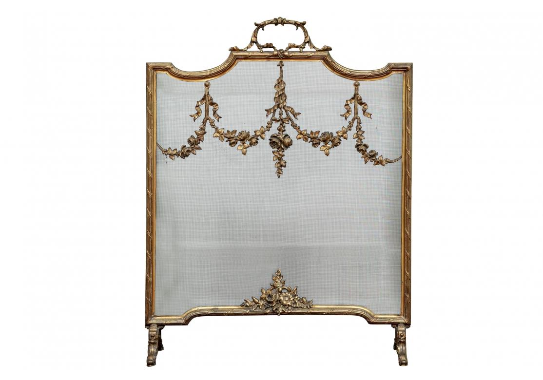 Écran de cheminée en bronze de style Louis XVI à la française, de forme carrée, la façade ornée de guirlandes de fleurs et de rubans. Le bord cannelé avec des rubans en volutes, une grappe de fleurs au bas de l'écran, une poignée en forme de