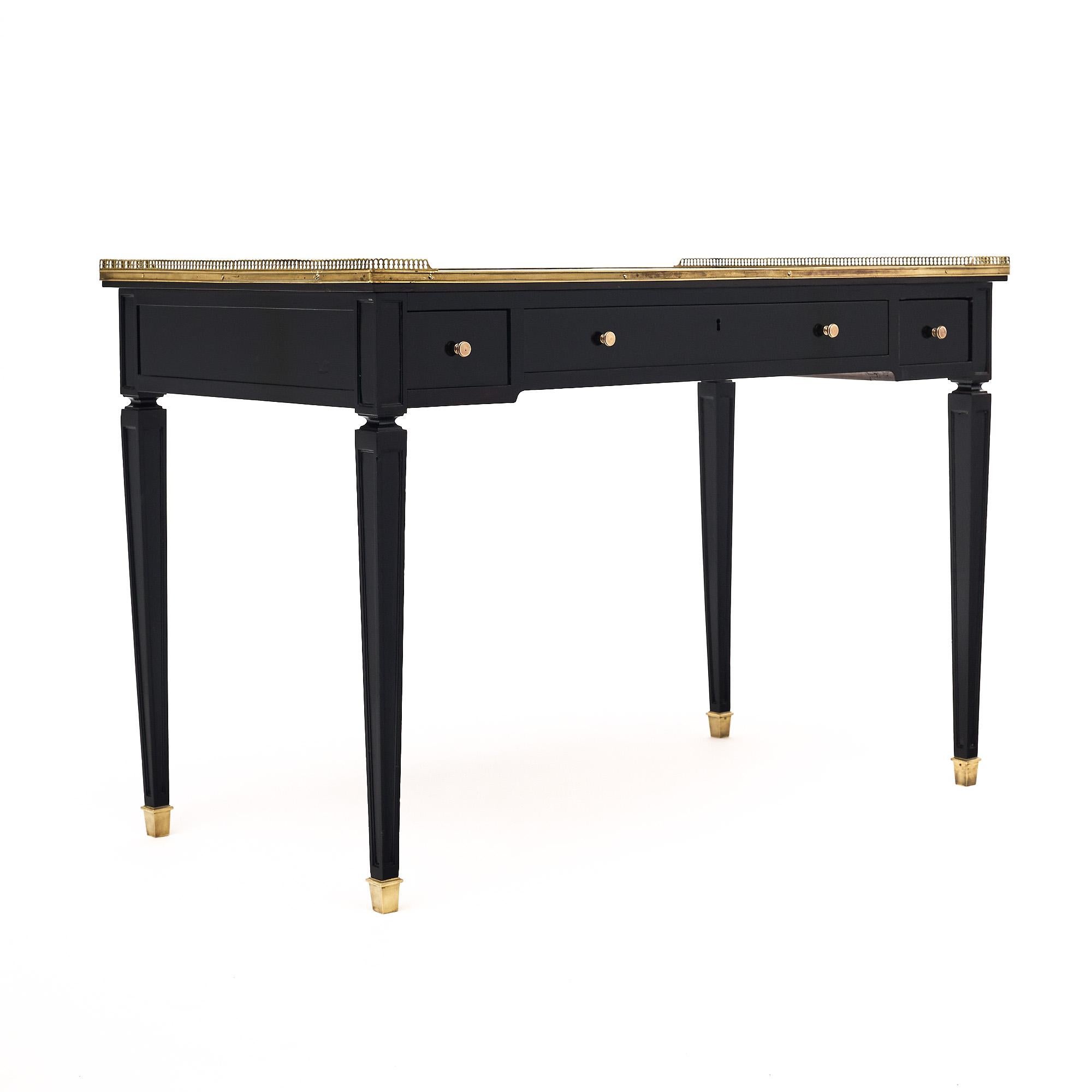 Writing desk from France in the Louis XVI style. This piece has been ebonized and finished with a lustrous French polish of museum-quality. There are four dovetailed drawers each with a brass knob. The tapered legs are capped in brass and the top is