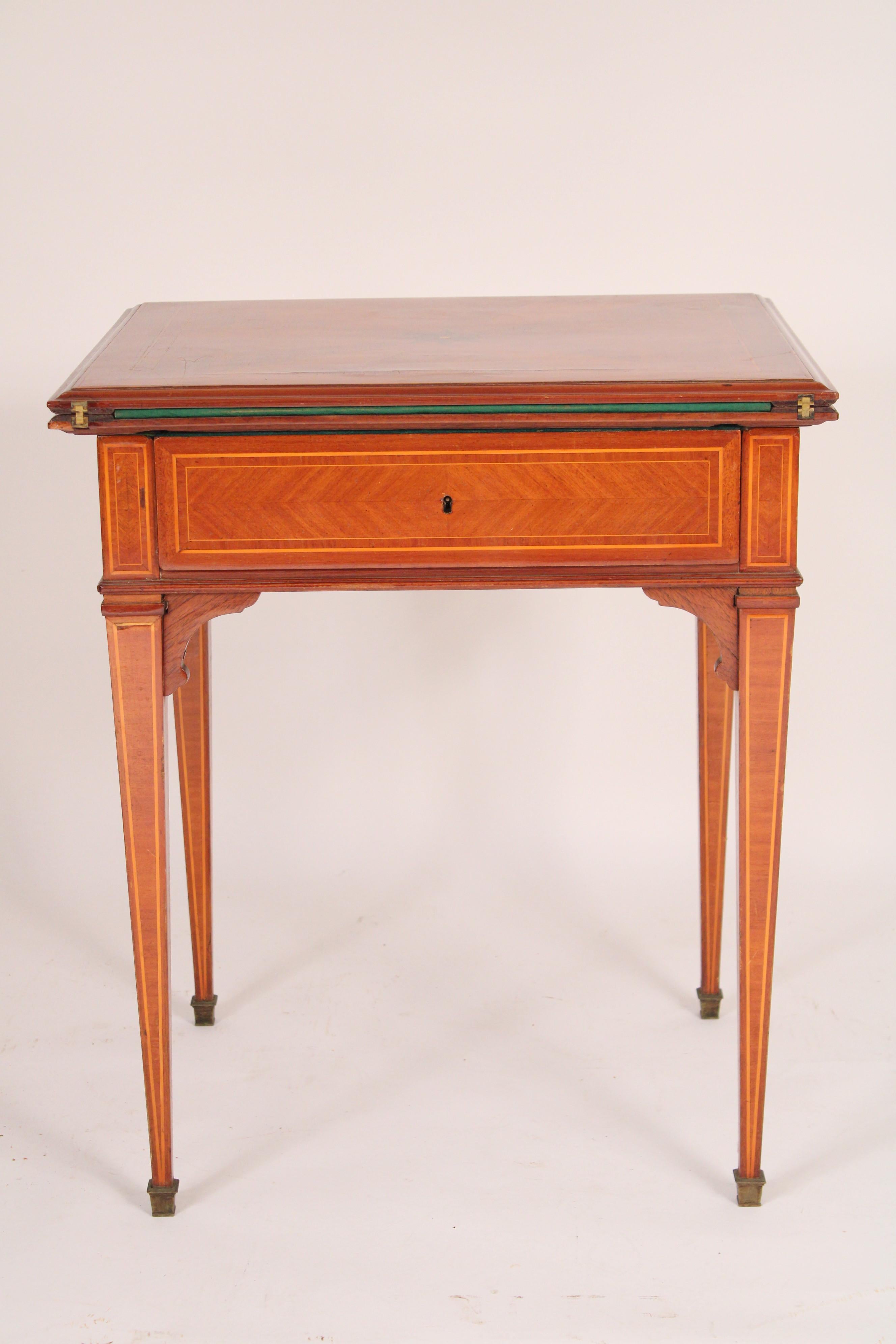 Louis XVI style tulip wood, birch and king wood fold over games table, circa 1930's. The top with a central star inlay, aprons with tulip wood panels framed with birch string inlay supported on square tapered legs ending in brass sabots. The playing