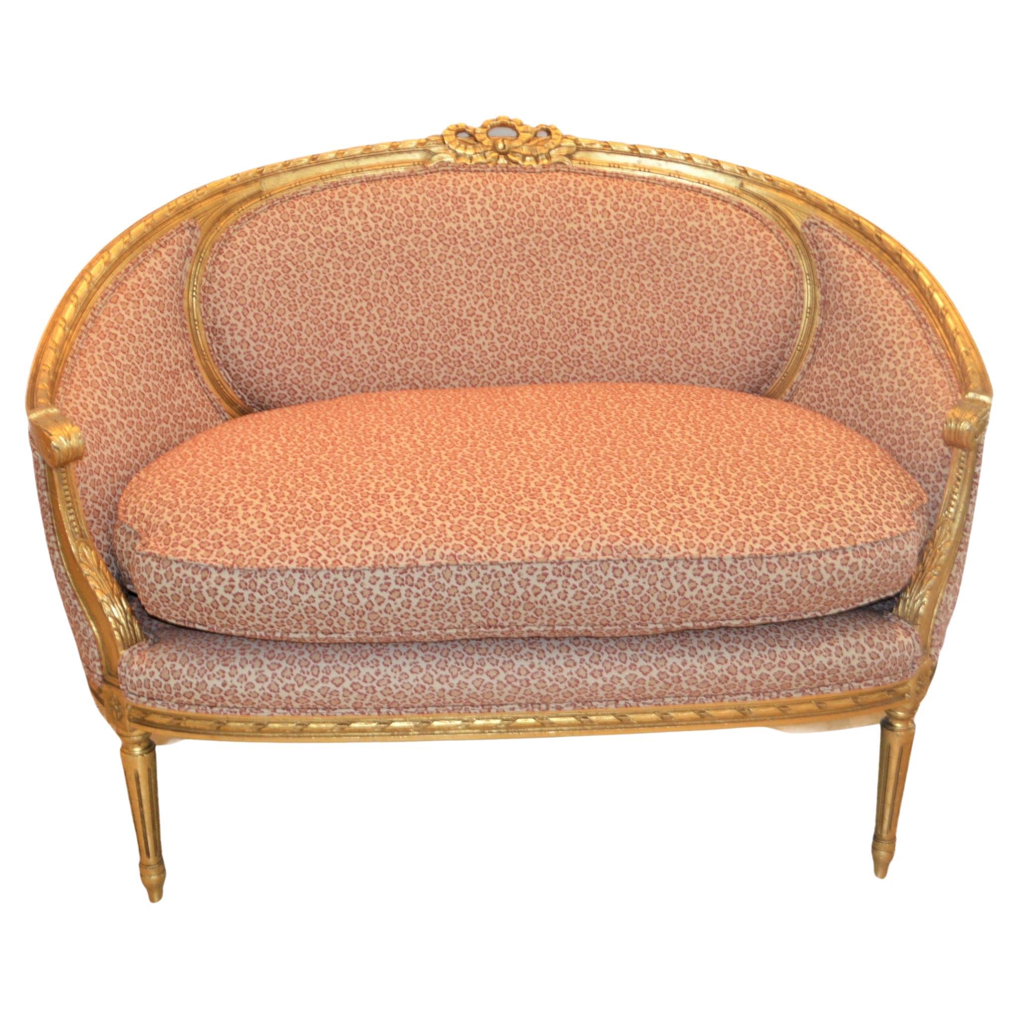 Louis XVI style gilded settee with pink and cream fabric.