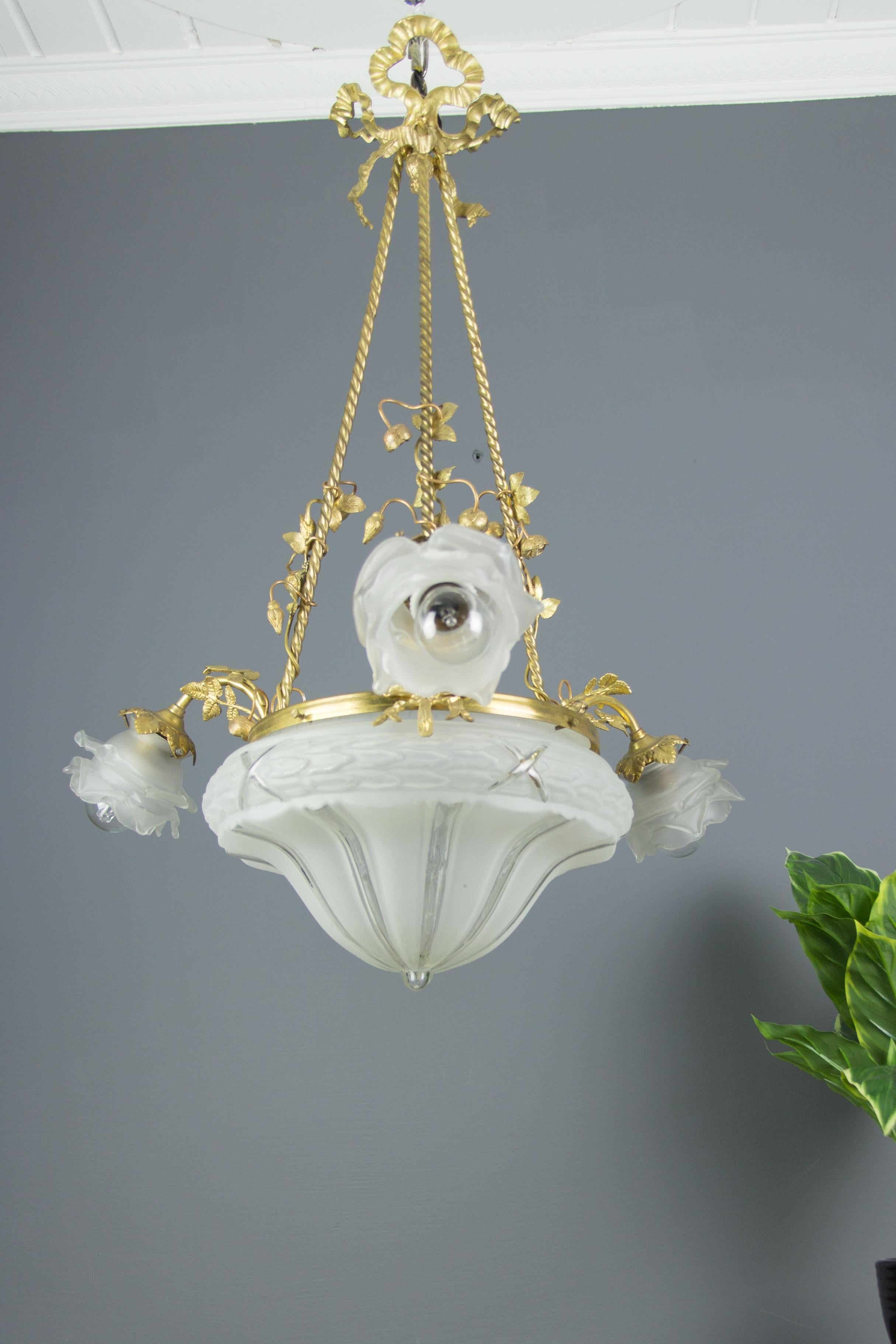 French Louis XVI style gilt bronze and frosted glass four-light chandelier, embellished with bronze flowers, has three arms, each with frosted glass floral shape lampshade and original E27 (E26) socket.
Measures: Height is 28.3 inches / 72 cm,