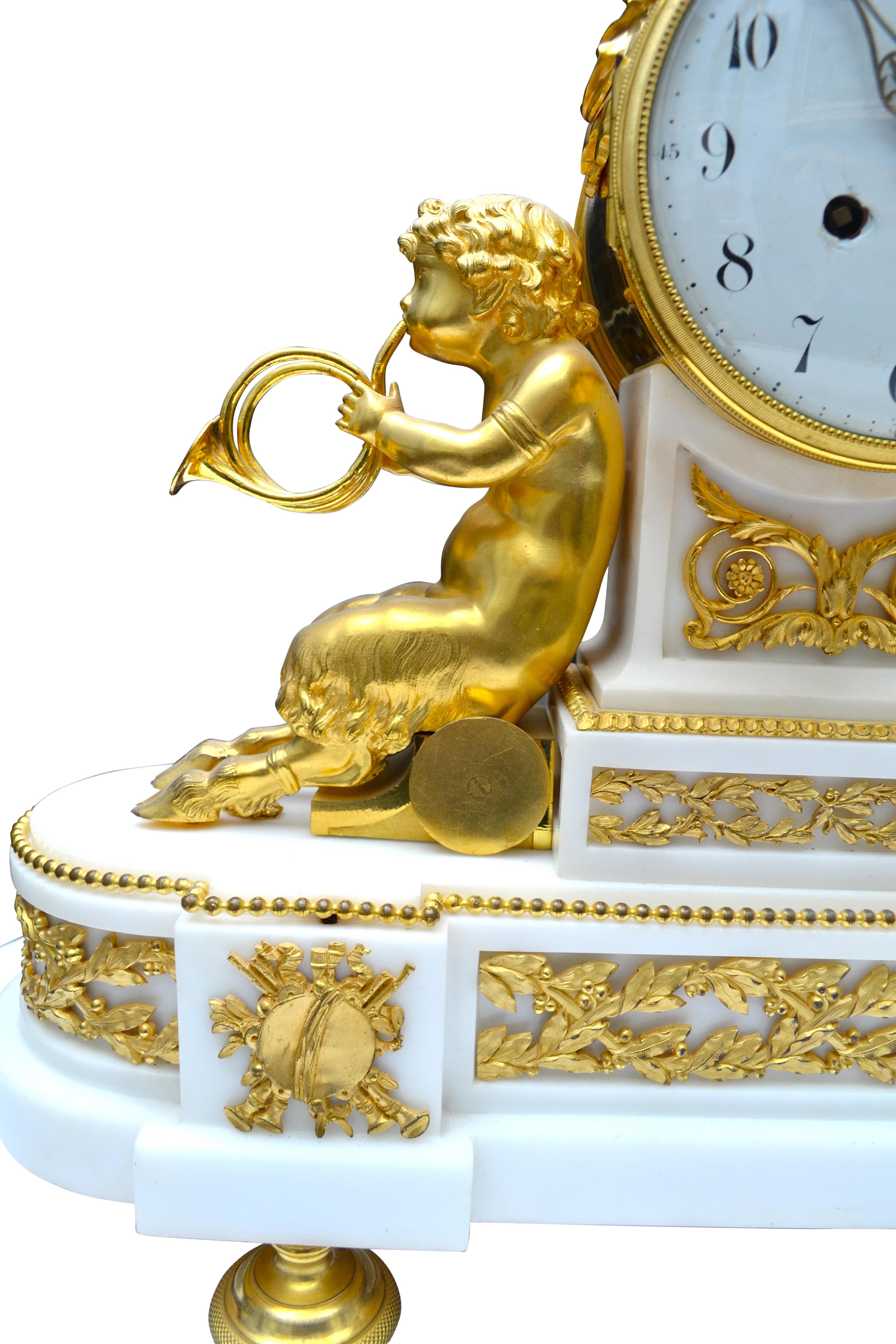 Louis XVI style clock with Bacchante and musical satyrs. The body of the clock features two young satyrs in gilded bronze each holding twin horns; they lean back against the shaped white marble clock plinth supporting the white enamel dial. Atop the