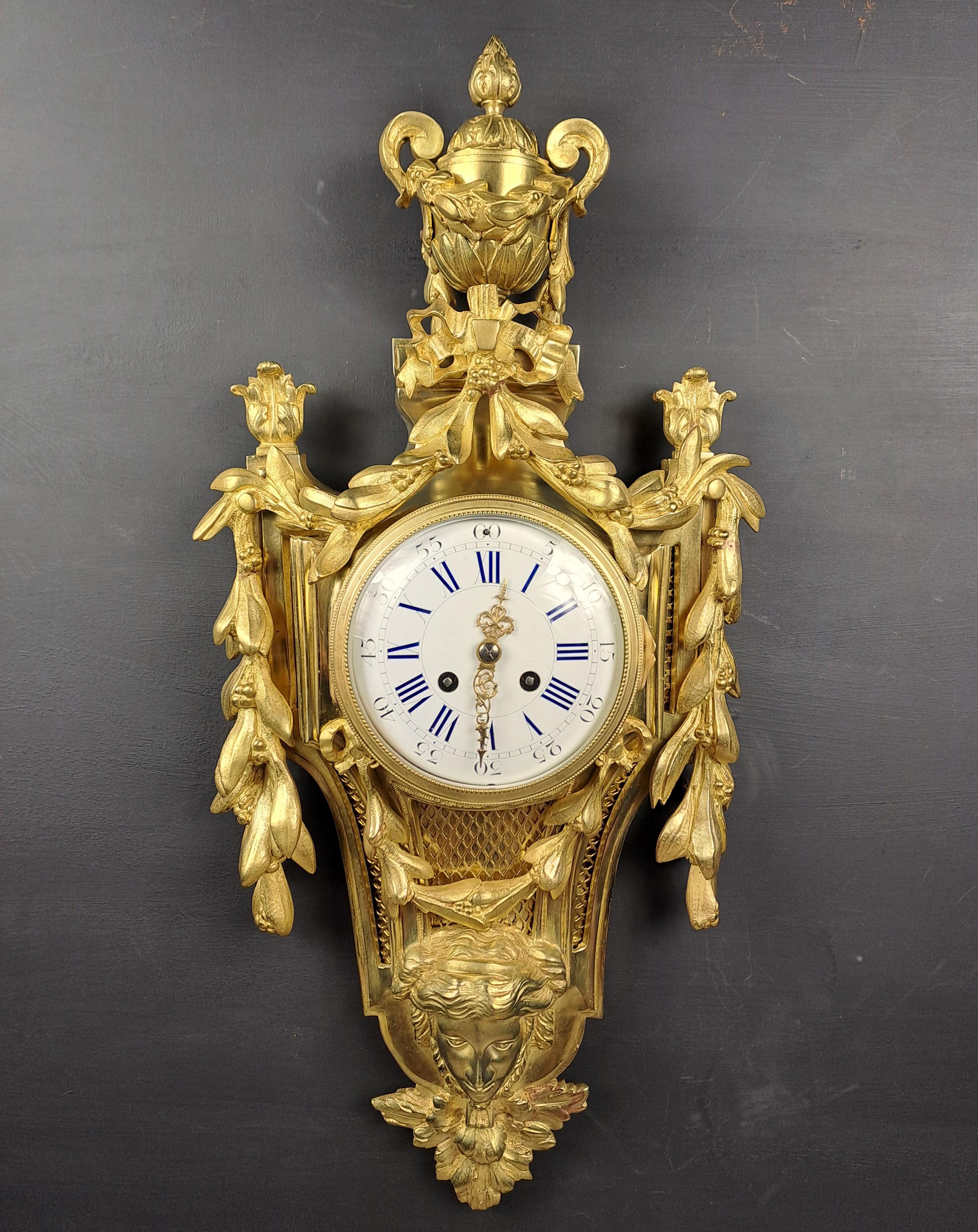 Große Kartelluhr im Louis-XVI-Stil aus fein ziselierter, vergoldeter Bronze mit reichem Dekor aus Pflanzengirlanden, Feuertopf und Maskaron, der ein weibliches Gesicht darstellt.

Qualitätsarbeit, Periode Napoleon III.

Sehr guter Zustand, mit