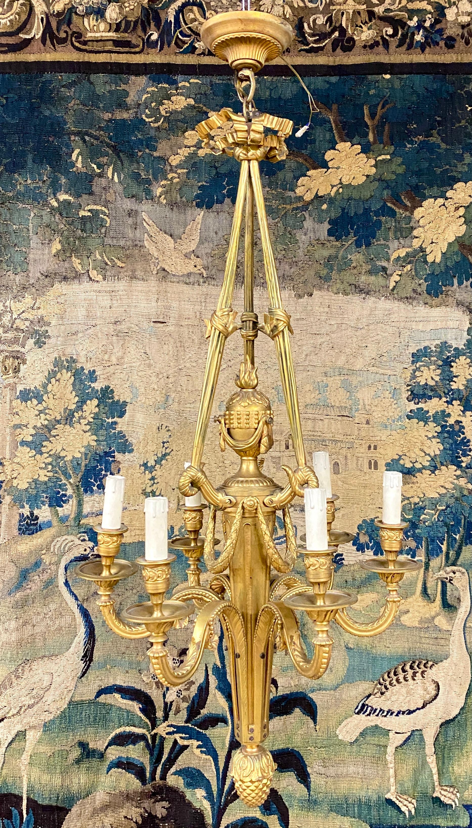 Louis XVI style gilt bronze chandelier with six sconces. it ends with a pine cone and is surmounted by a ribbon specific to the Louis XVI style. The barrel is decorated with garlands and a burning cassolette. Good quality screw mounting and