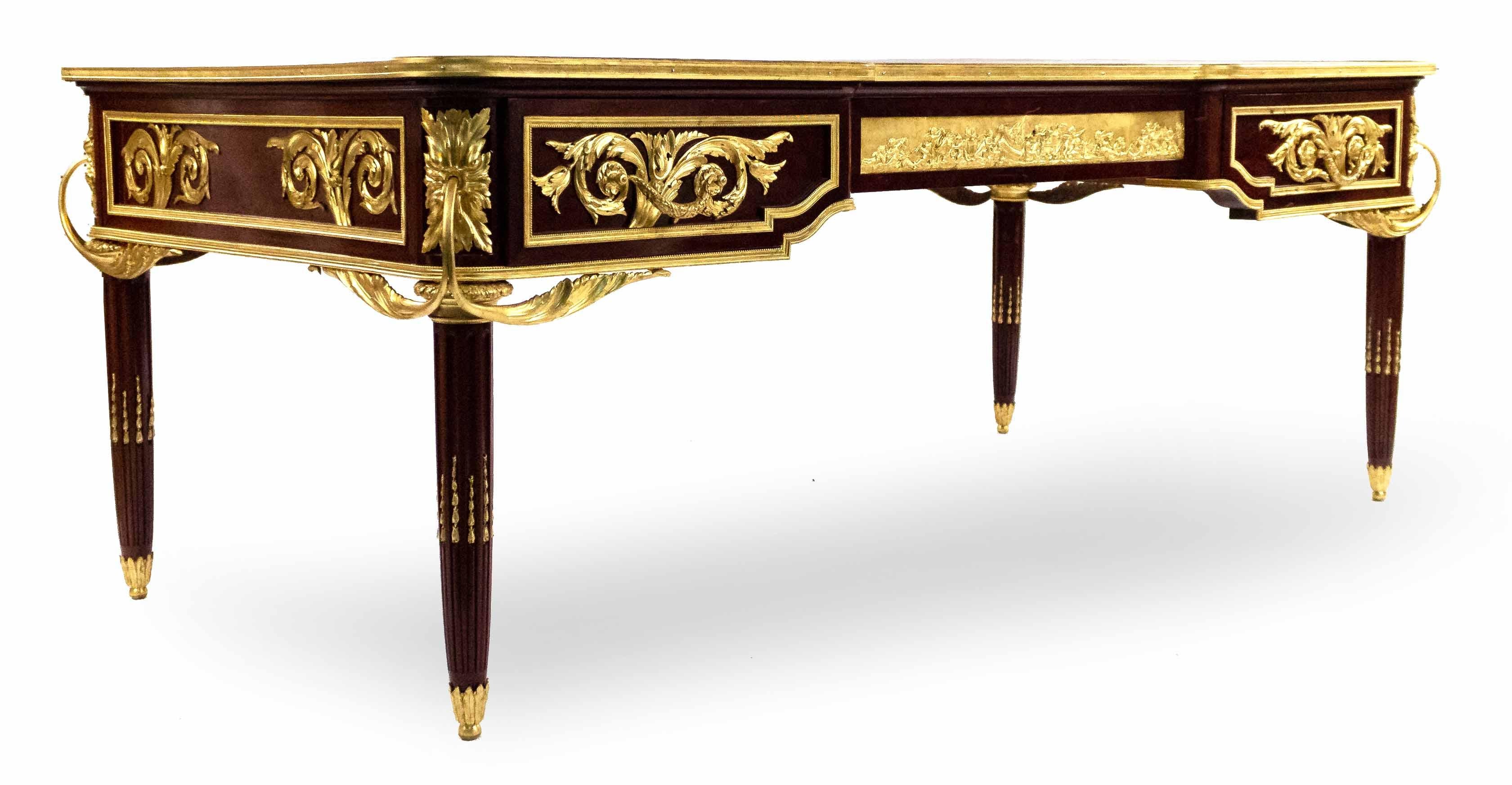 Louis XVI style (19th-20th century) gilt bronze mounted 3-drawer bureau plat desk having a center plaque depicting an allegorical putti scene with a gold embossed leather top.
