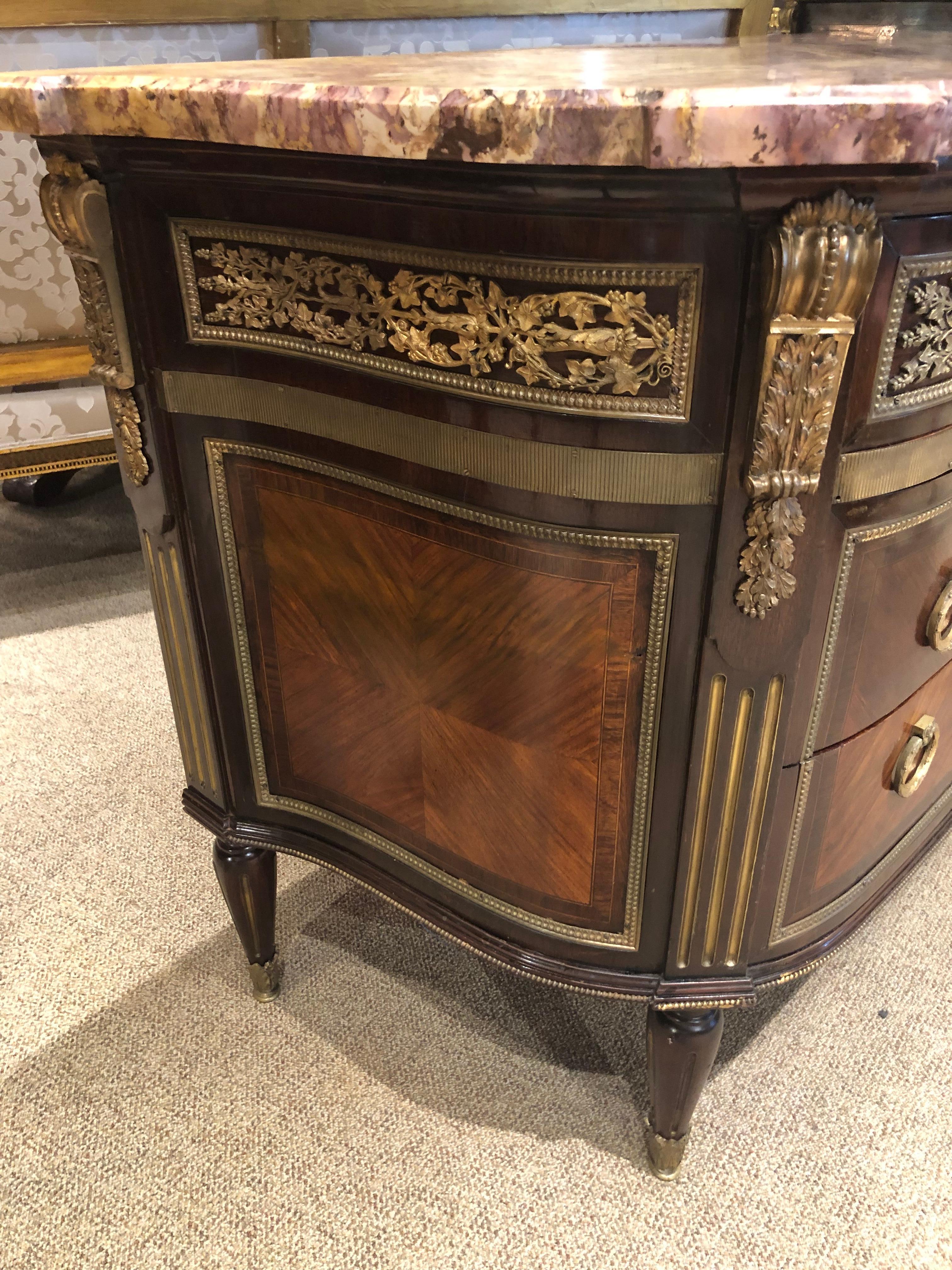 Louis XVI style gilt bronze mounted commode 19th century marble top of breakfront form having three drawers
with working key. The bronze mounts depict leaf
and berry design. The sides curve gracefully toward
the back of this cabinet. Drawers