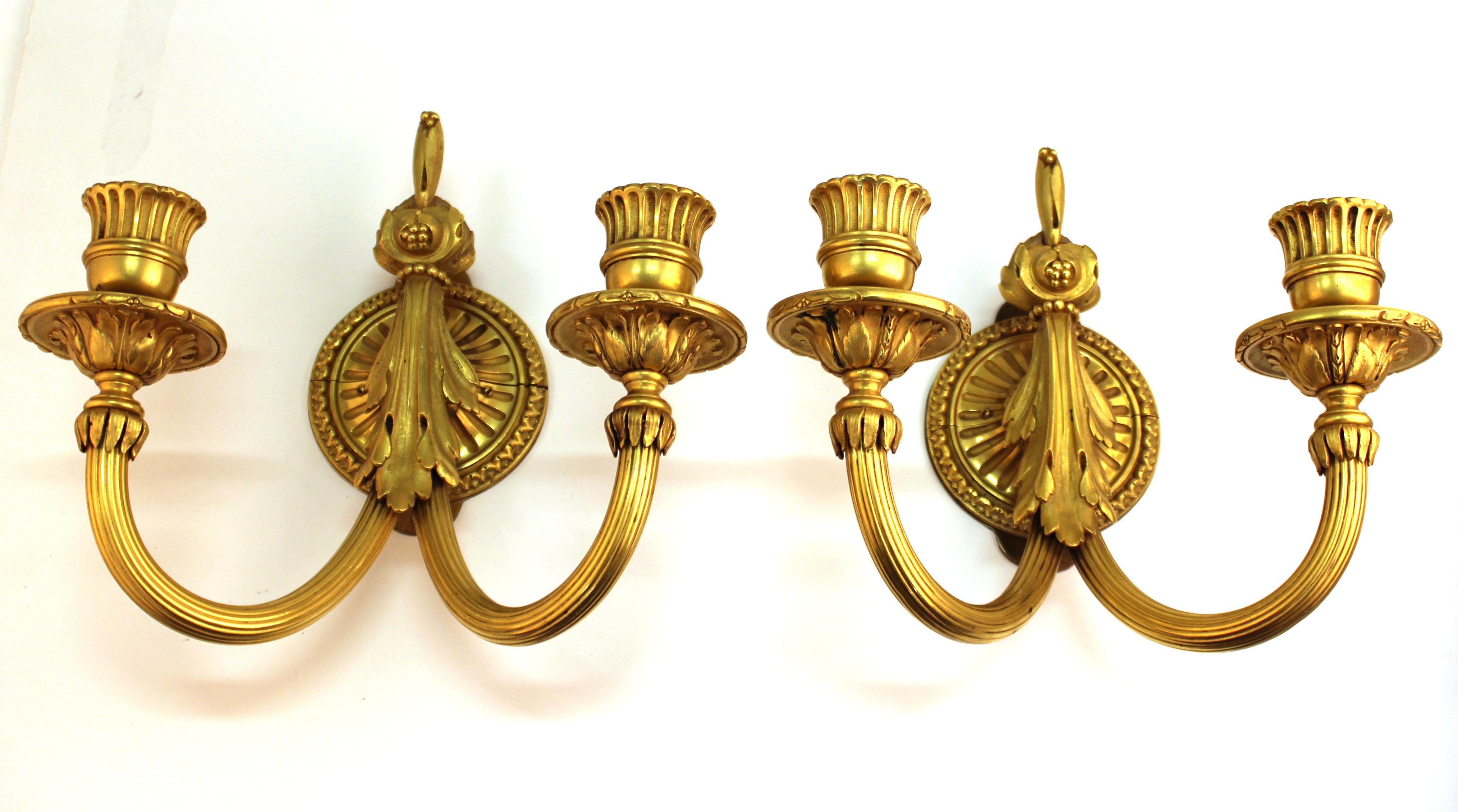 Louis XVI style pair of wall-mounted candle sconces in gilt bronze, with two candle sockets each. The pair is in great vintage condition and was likely made in Europe in the late 19th-early 20th century.