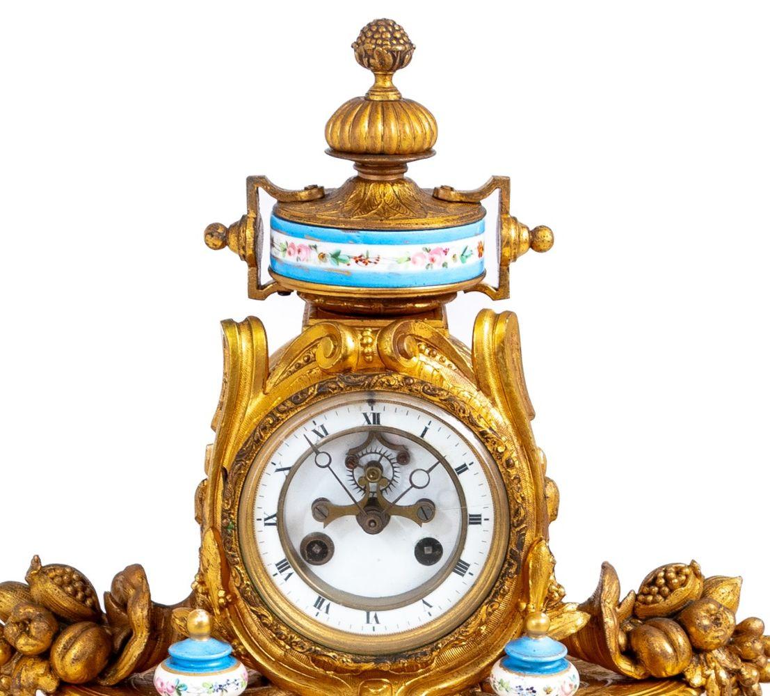 Pendule de cheminée en métal doré et porcelaine de Sèvres de style Louis XVI, fin du XIXe siècle, le cadran en émail blanc avec échappement ouvert, le mouvement à sonnerie, le boîtier flanqué de chérubins assis, de colonnes, de cornes d'abondance et