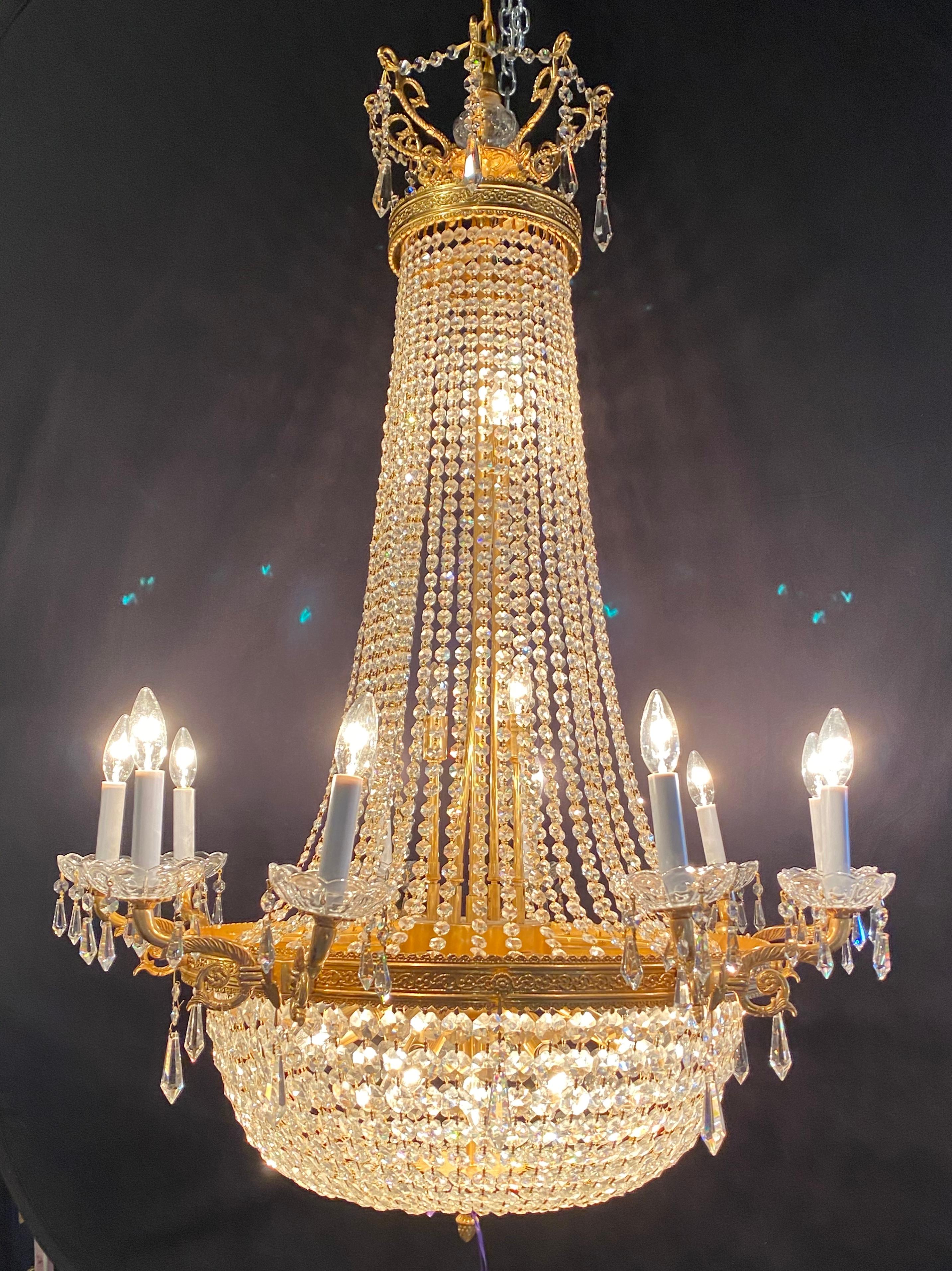 Louis XVI style gilt metal chandelier having five double light arms and sixteen interior lights. The case having been fully reguilded and rewired in a neoclassical fashion with draping crystals and a basket form crystal bottom.
 