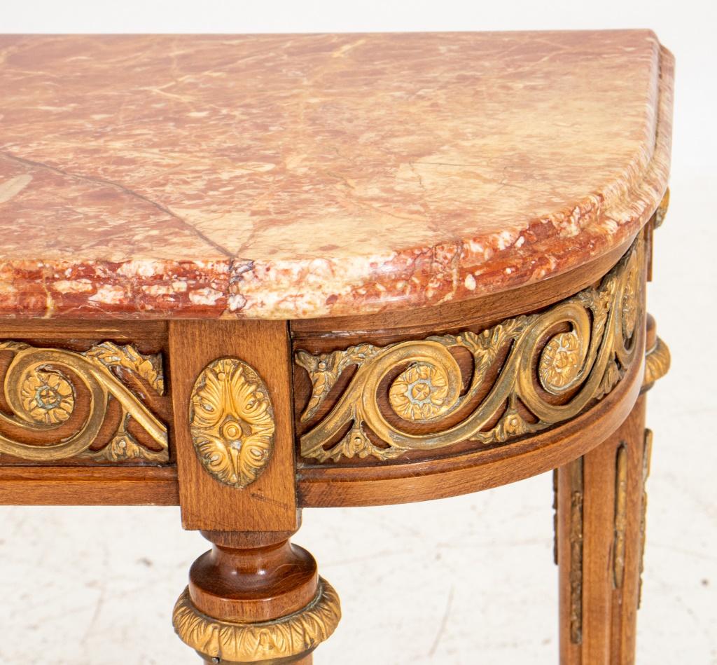 Louis XVI style gilt metal mounted console of d-shaped form with conforming breche d'abricot marble top, the apron to vitrucian scrollwork mounts, above tapering columnar stop fluted legs with mounts on toupie feet.
Dimensions: 30