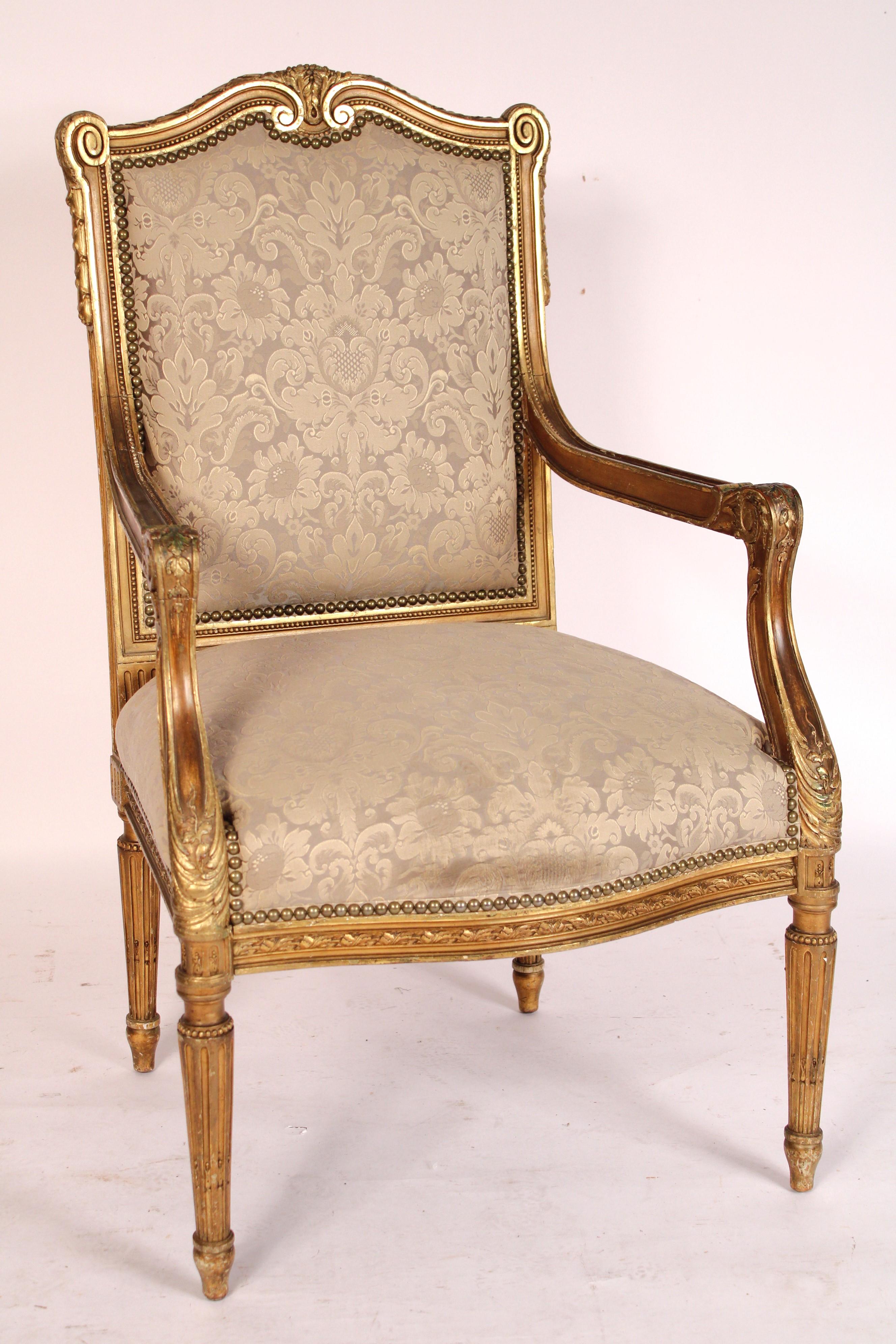 Louis XVI style gilt wood armchair, circa 1900. With a foliate carved cupids bow crest rail, down swept arms with beaded carvings ending in acanthus carvings, foliate carved apron, turned tapered fluted legs. The gilt wood decoration is a