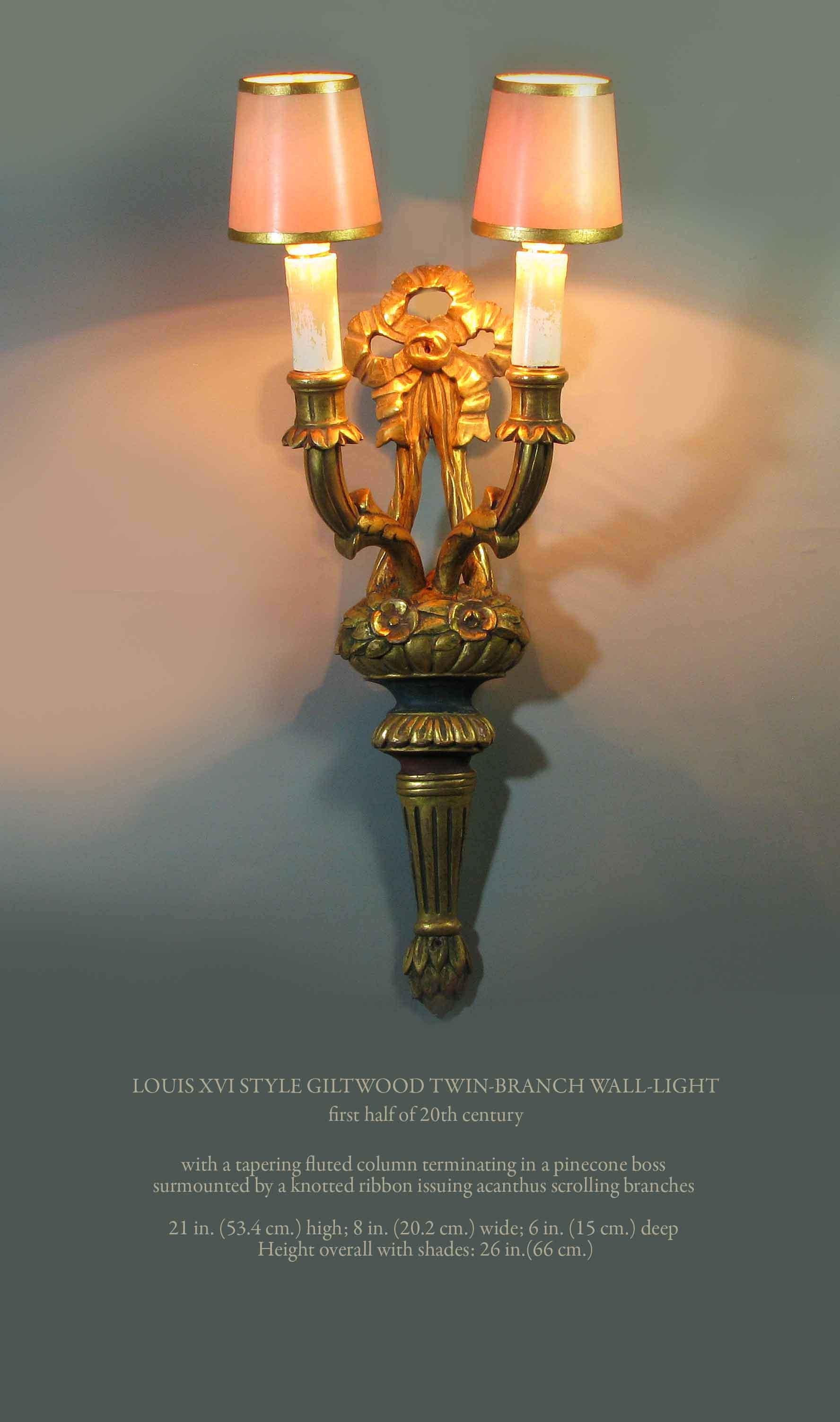 LOUIS XVI STYLE GILTWOOD TWIN-BRANCH WALL-LIGHT
first half of 20th century

With a tapering fluted column terminating in a pinecone boss 
surmounted by a knotted ribbon issuing acanthus scrolling branches.

Measures: 21 in. (53.4 cm.) high.
8