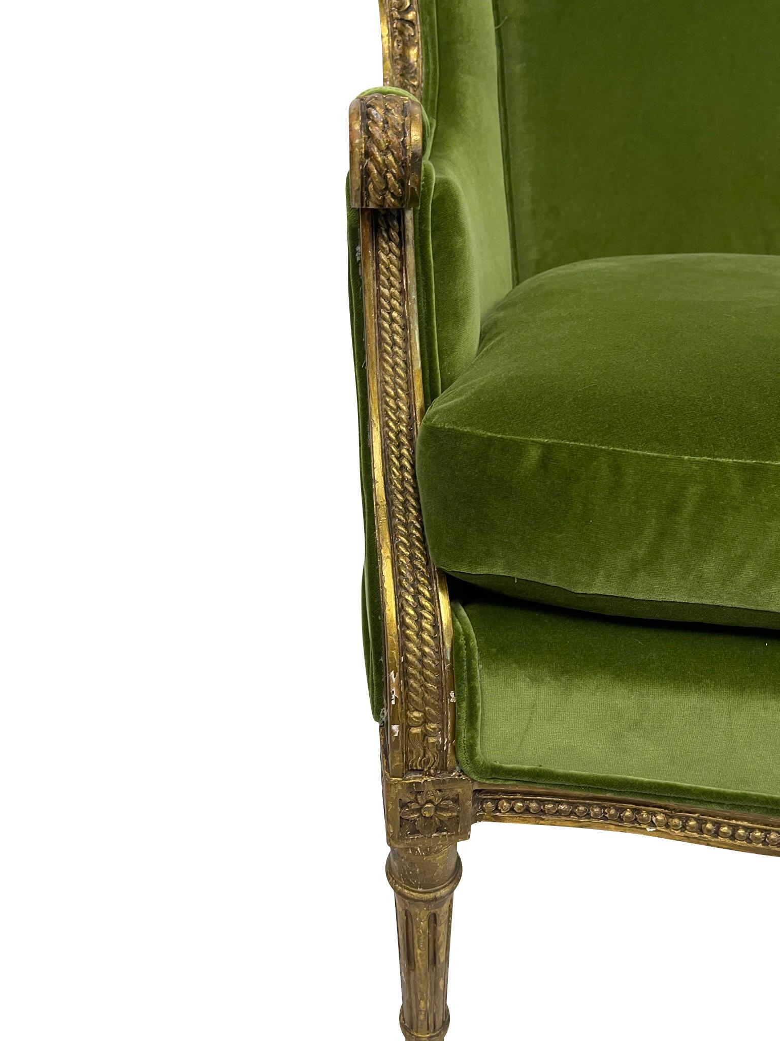 Early 20th or late 19th century Louis XVI Bergere wing chair in carved giltwood.  High comfortable back with lovely foliate carved detail around the back of the wing, ending in reeded arms with rope detail and reeded legs ending in toupie feet.  The