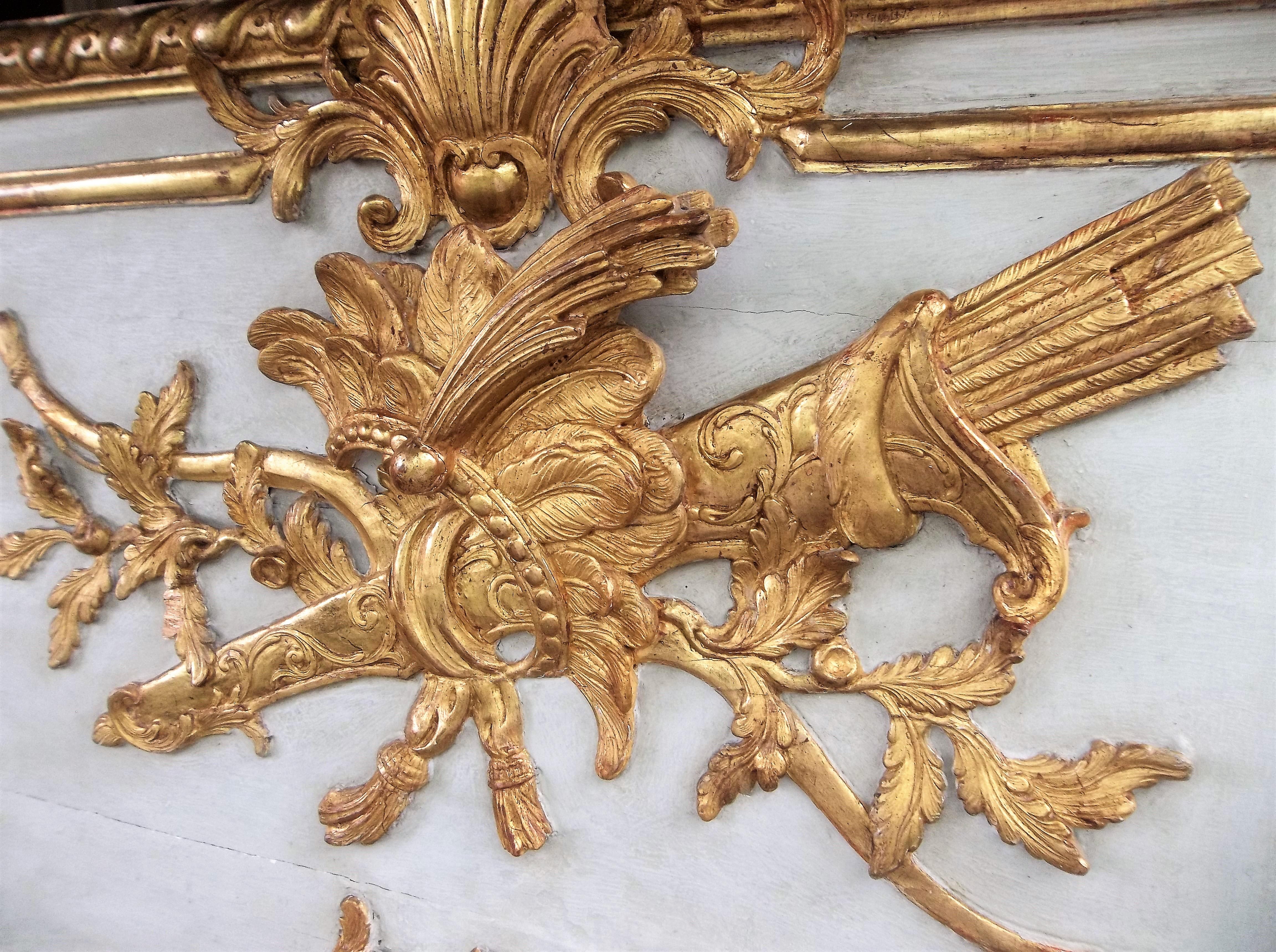 French Louis XVI trumeau mirror with raised gilt bow and quiver with feathered headdress in relief. Water gilt and matte gilding throughout.

Most likely  from a room of boiserie (niches on back indicate paneling attachment) the crème paint with