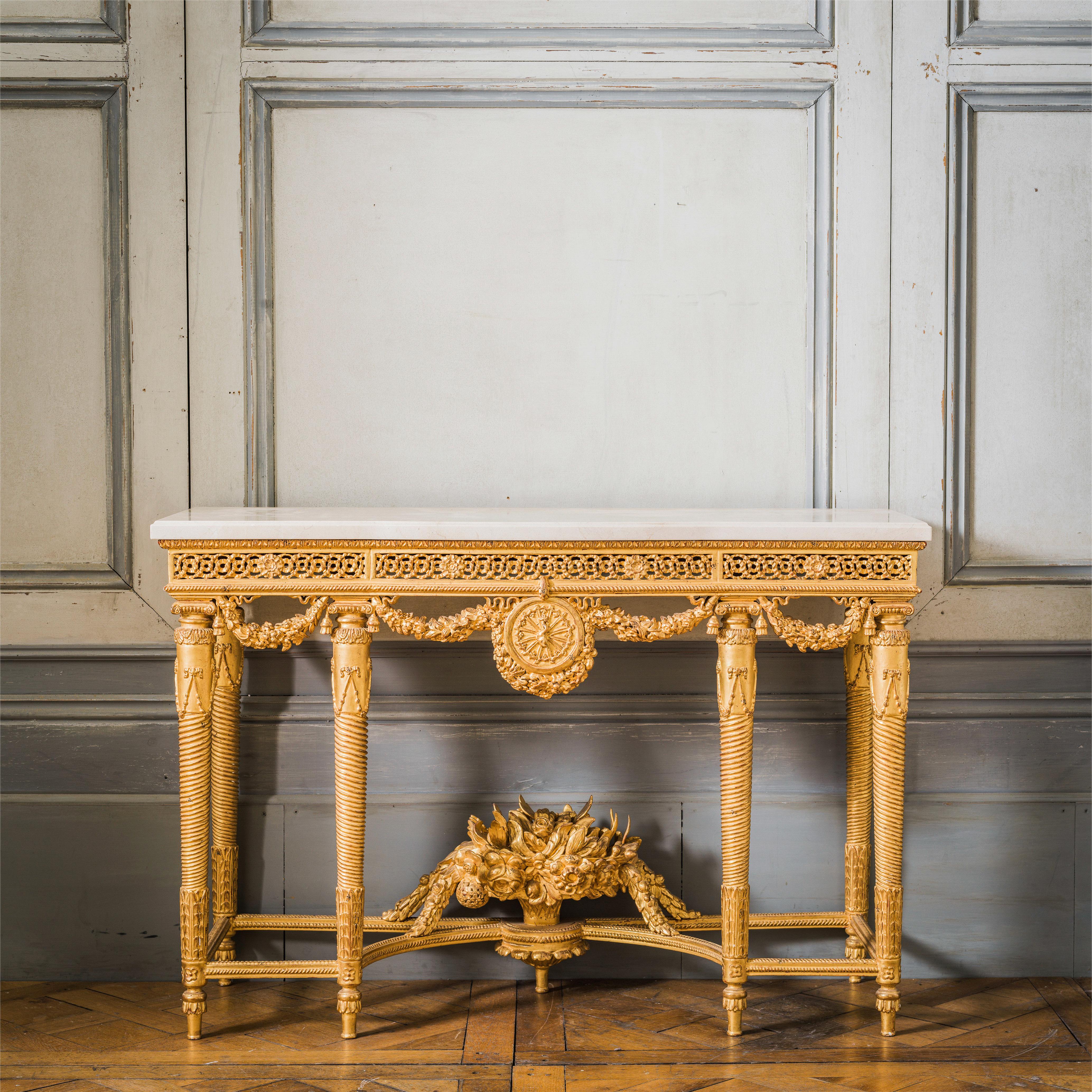 Consoles en bois doré de style Louis XVI : Réalisées par des maîtres artisans, élégamment sculptées et finies à la main dans une patine dorée à l'eau à la feuille d'or 23,75 carats. Dessus en marbre Crema Marfil biseauté de 30 mm.
Nous en avons 2