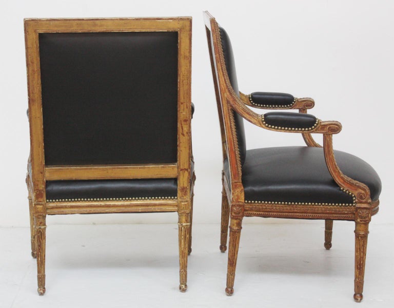 A pair of Louis XVI-style worn / faded (more wood than gold) giltwood fauteuils / open armchairs with new black leather upholstery and nailhead trim, France, 19th century

$6,800.00 the pair.