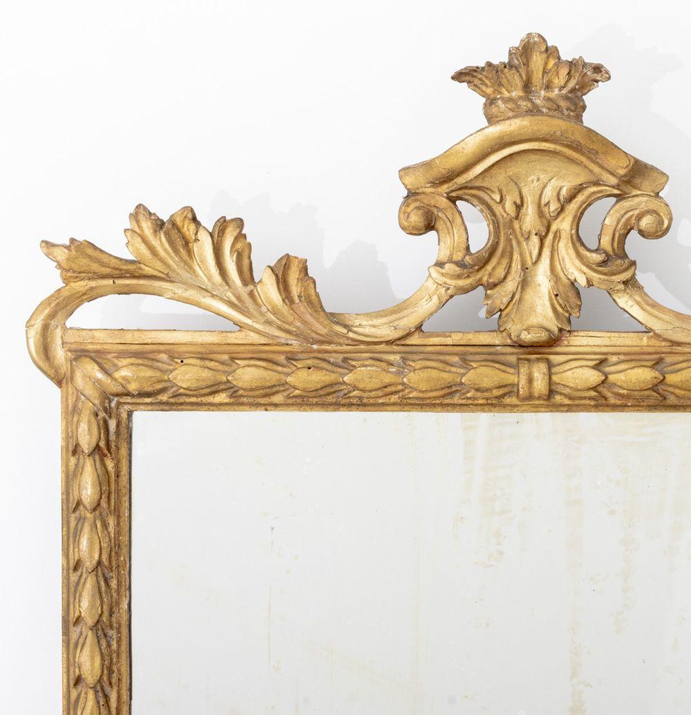 Miroir en bois doré de style Louis XVI, 19ème siècle, avec un bouclier et une crête en forme de volute avec une bordure florale sculptée. Plaque de miroir : 30