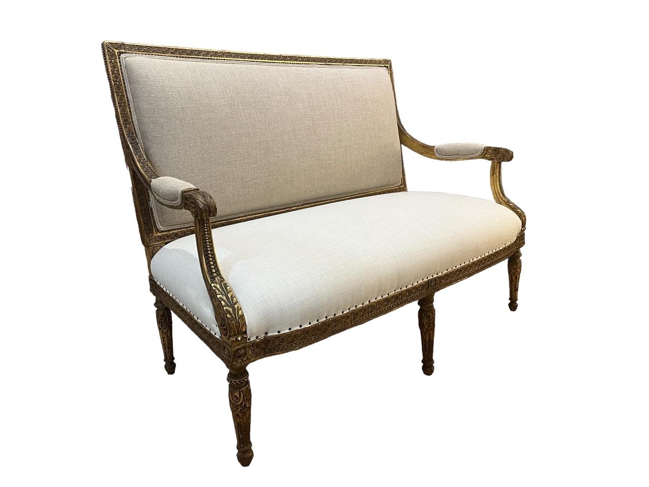 This Louis XVI Style Giltwood Settee exudes timeless elegance with its intricate giltwood frame, meticulously crafted in the 18th-century French aesthetic. Adorned with delicate carvings and fluted legs, it epitomizes the neoclassical refinement