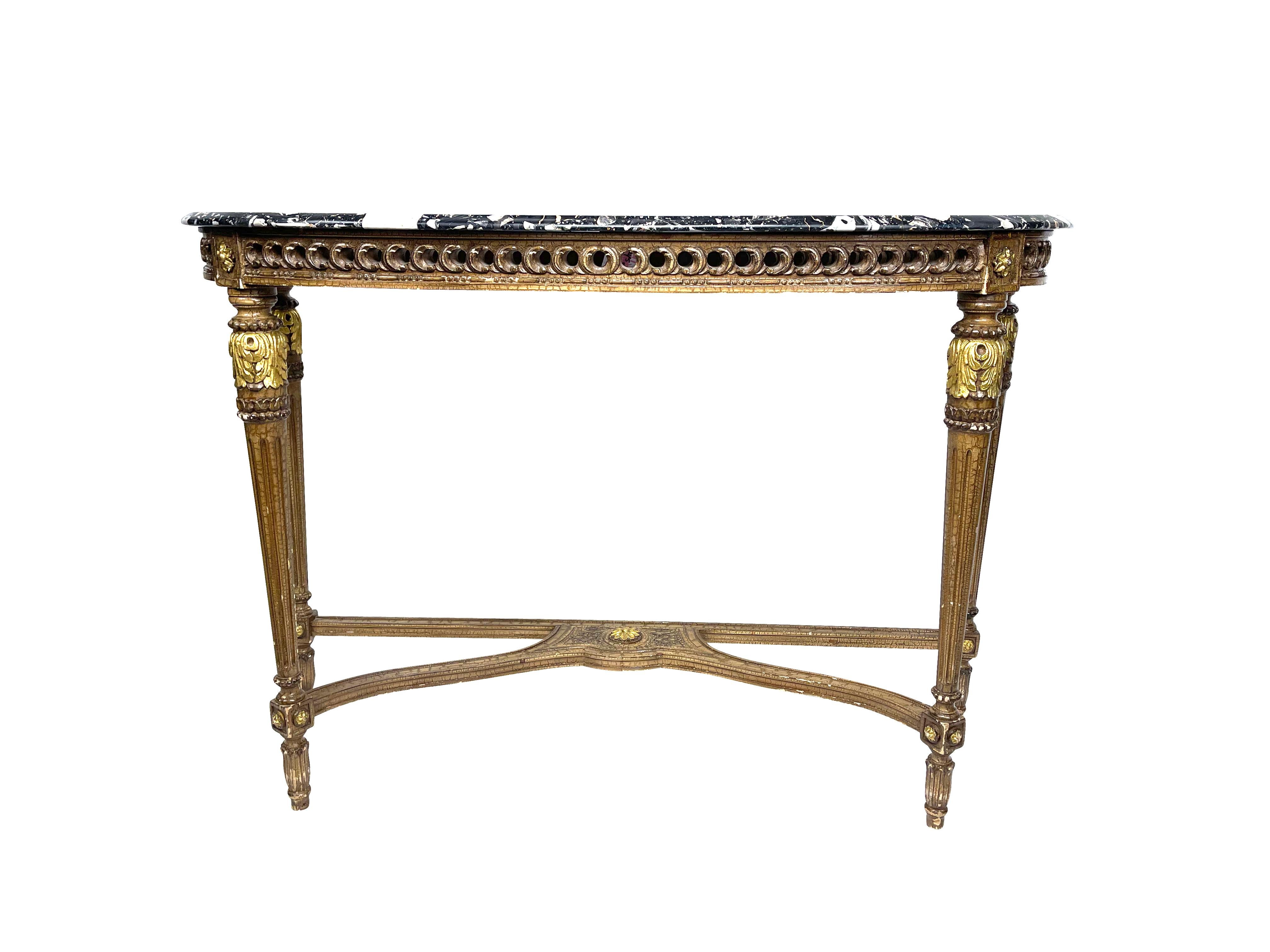 Louis XVI style gold gilt console table with black marble top. Beautifully carved with rosette, and foliate decoration on the base, reeded legs and intricately carved with a pierced gallery below the marble top, The black marble is speckled with