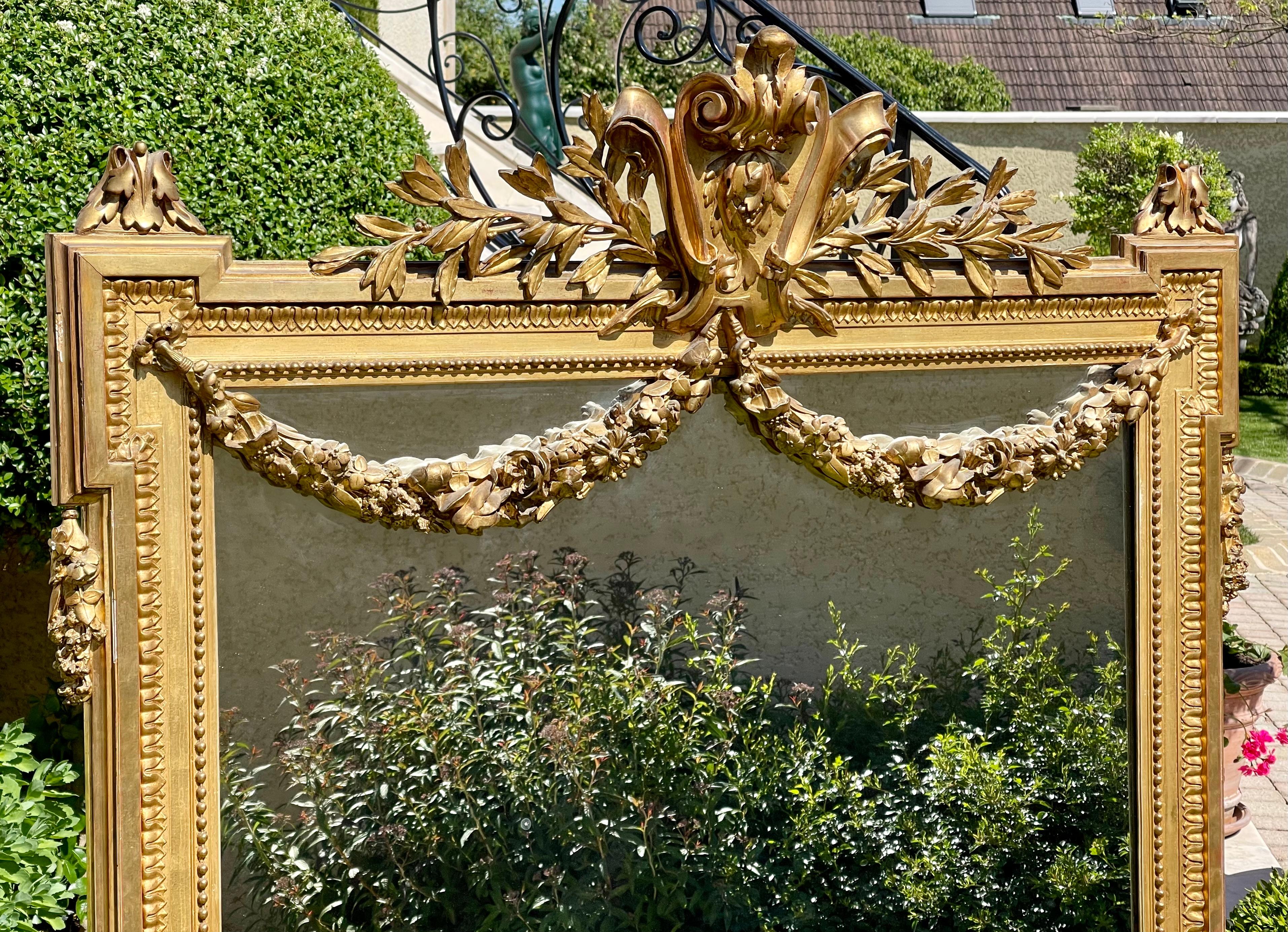 Superb Louis XVI style mirror in gilded plaster. Decorated with garlands of flowers and bay leaves. Good condition.