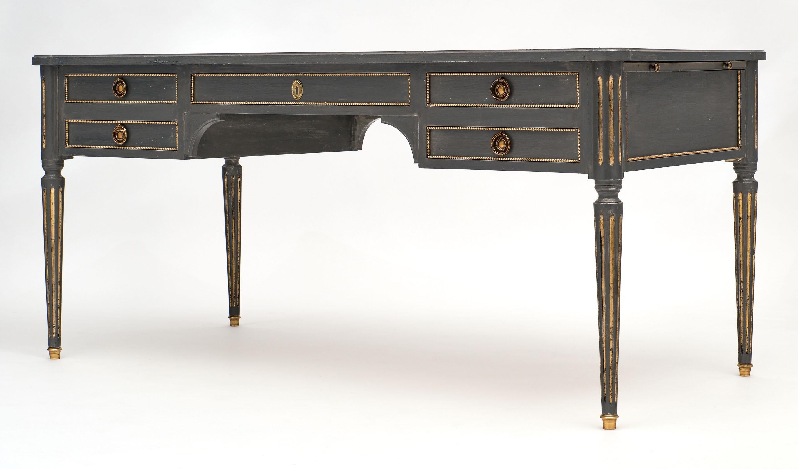A fine French Antique grand Louis XVI style gray painted desk with important proportions and five dovetailed drawers with their original finely cast bronze hardware. The desk is made of cherrywood and features gilt brass and 24 carat gold leaf