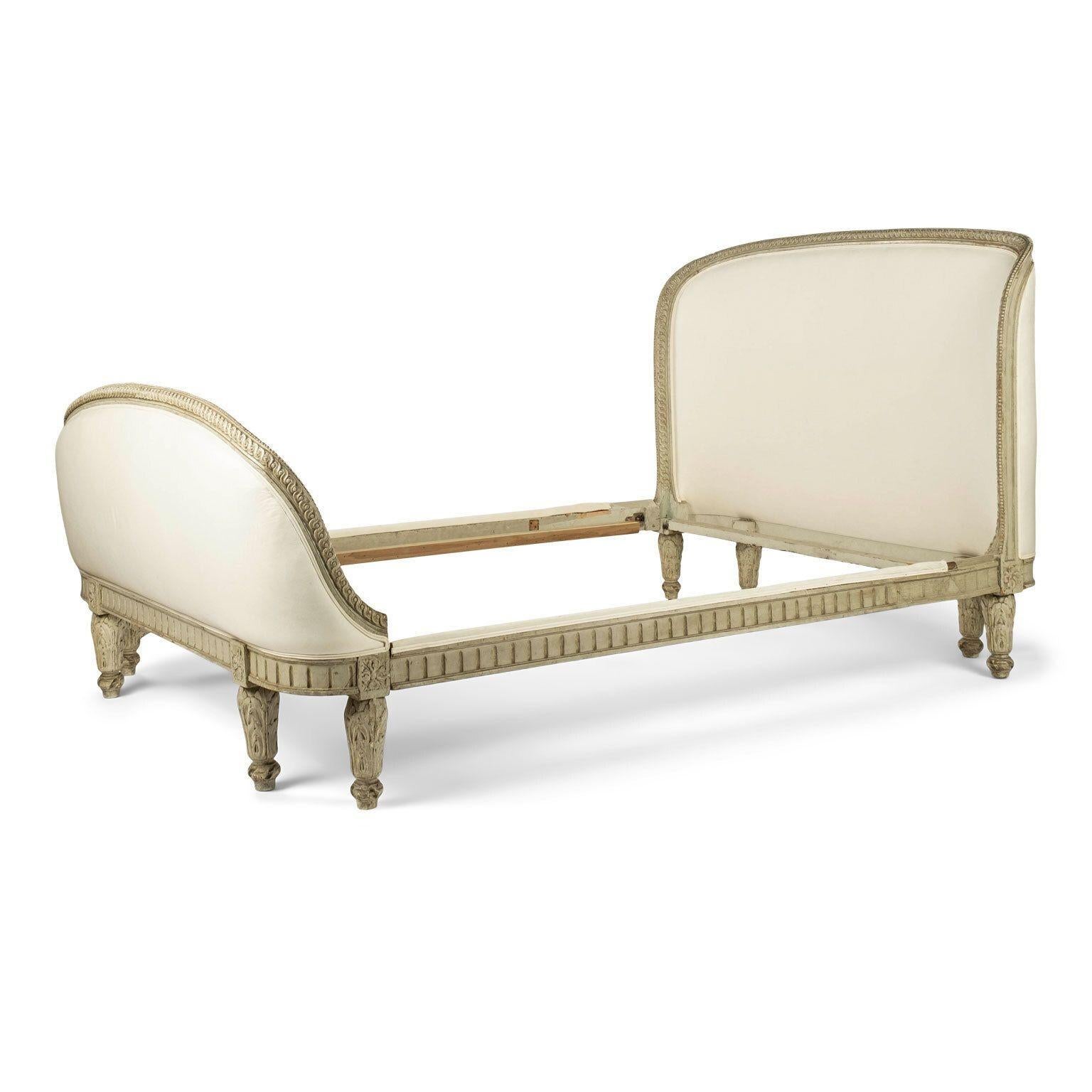 Louis XVI style green-gray painted full size (double) bed dating to late 19th century. Intricately hand-carved side rails, head and foot boards. Later - but not recent - green-gray painted finish. Upholstered in off-white muslin. Accommodates a full