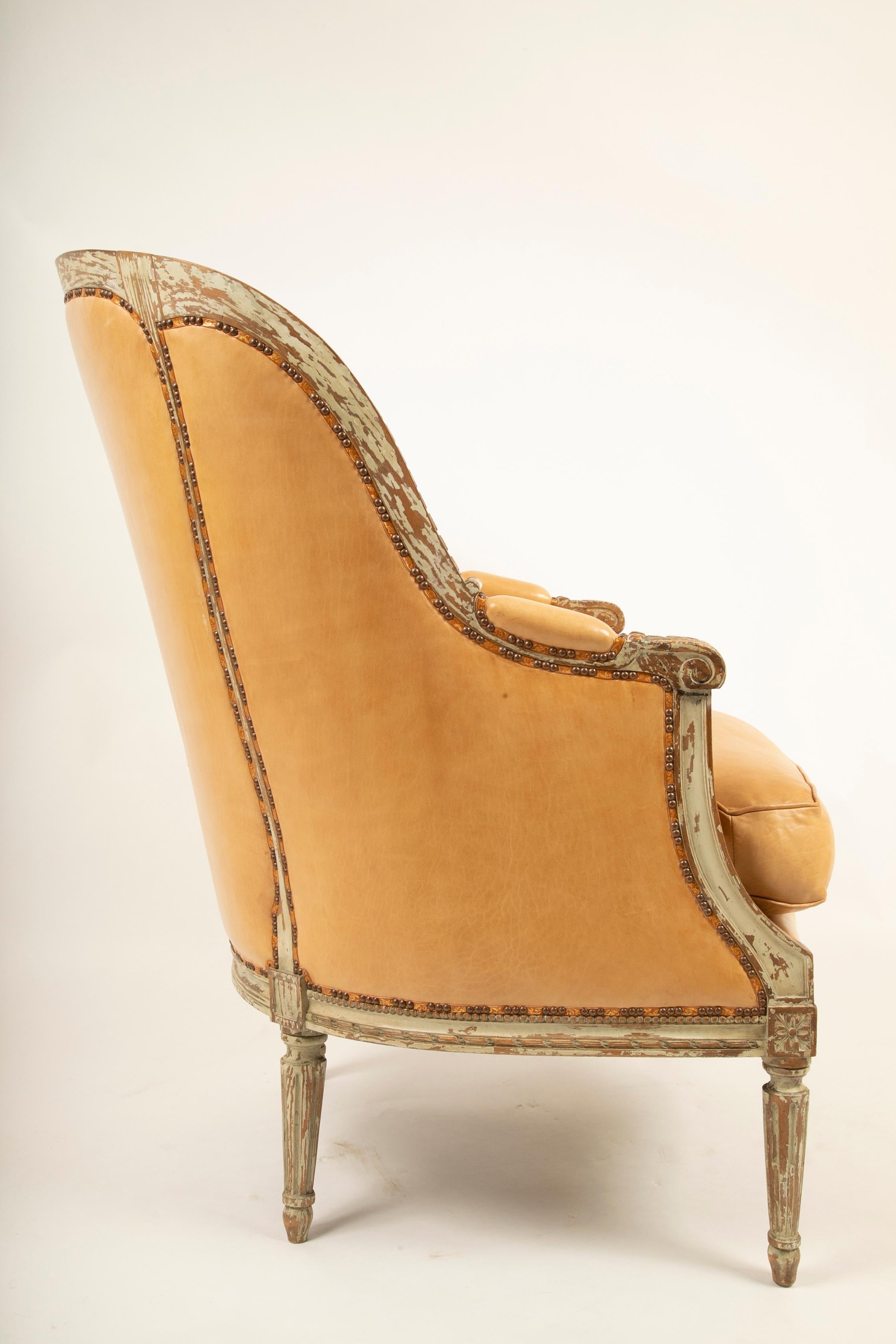 An exceptionally large grey painted Louis XVI style bergère. Upholstered in very high quality leather with parcel gilt leather tape and stop/group decorative tacking, circa late 19th century four available, priced individually.