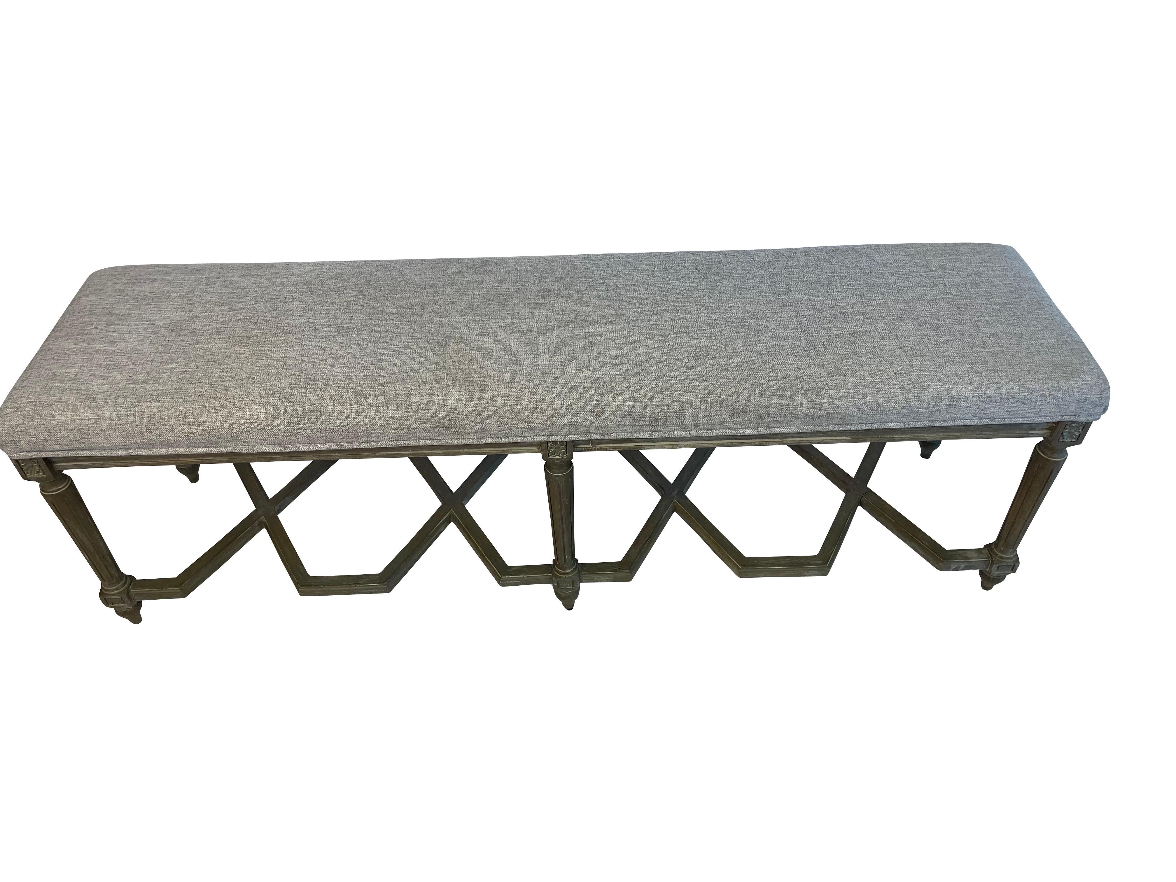 Attractive updated Louis XVI grey-painted bench with interesting hexagonal crossbar support on the bottom. Painted in a lustrous grey paint and newly professionally upholstered in a durable grey linen look fabric. Reeded legs ending in the typical