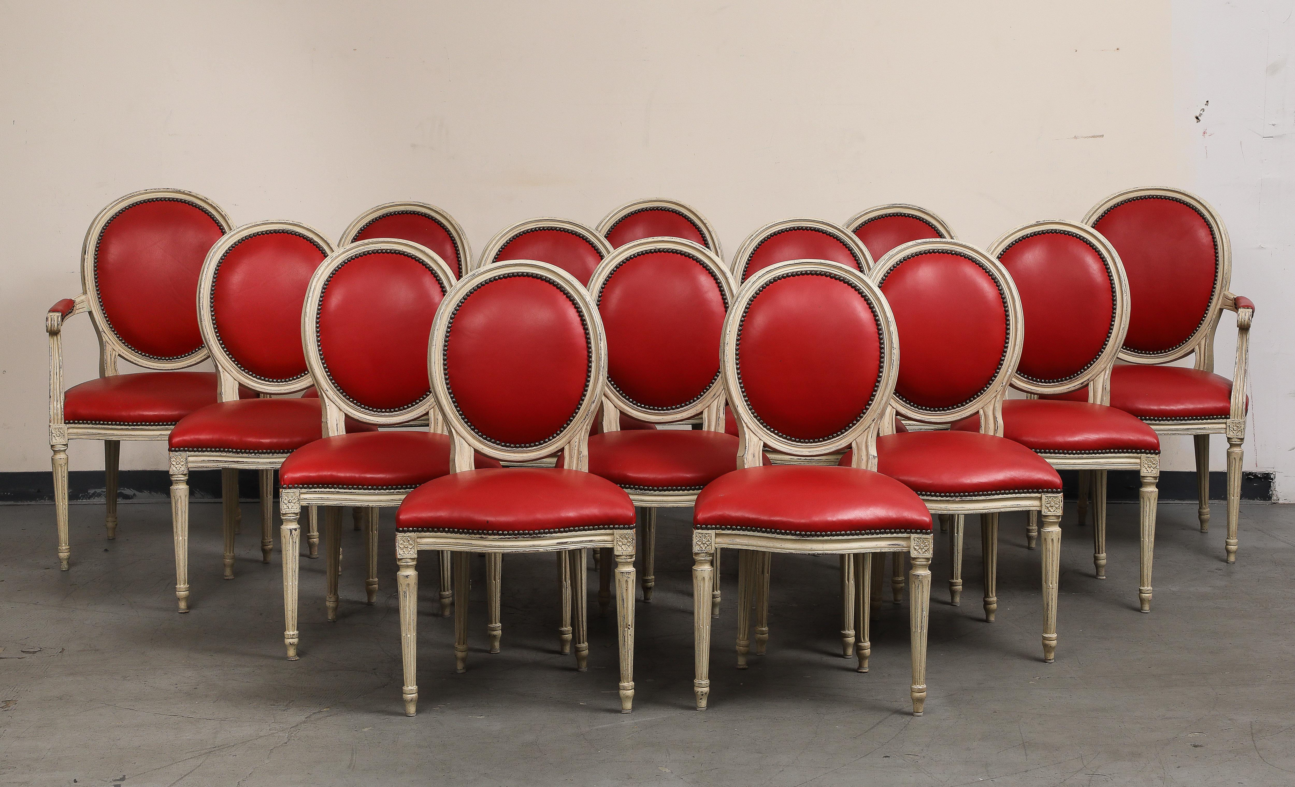 Groupe de quatorze (14) chaises de style Louis XVI en bois peint en grisaille avec sièges et dossiers en cuir rouge par Baker Furniture. Fin du 20e siècle. 
Marqué Baker Furniture en laiton sur la face inférieure. 

