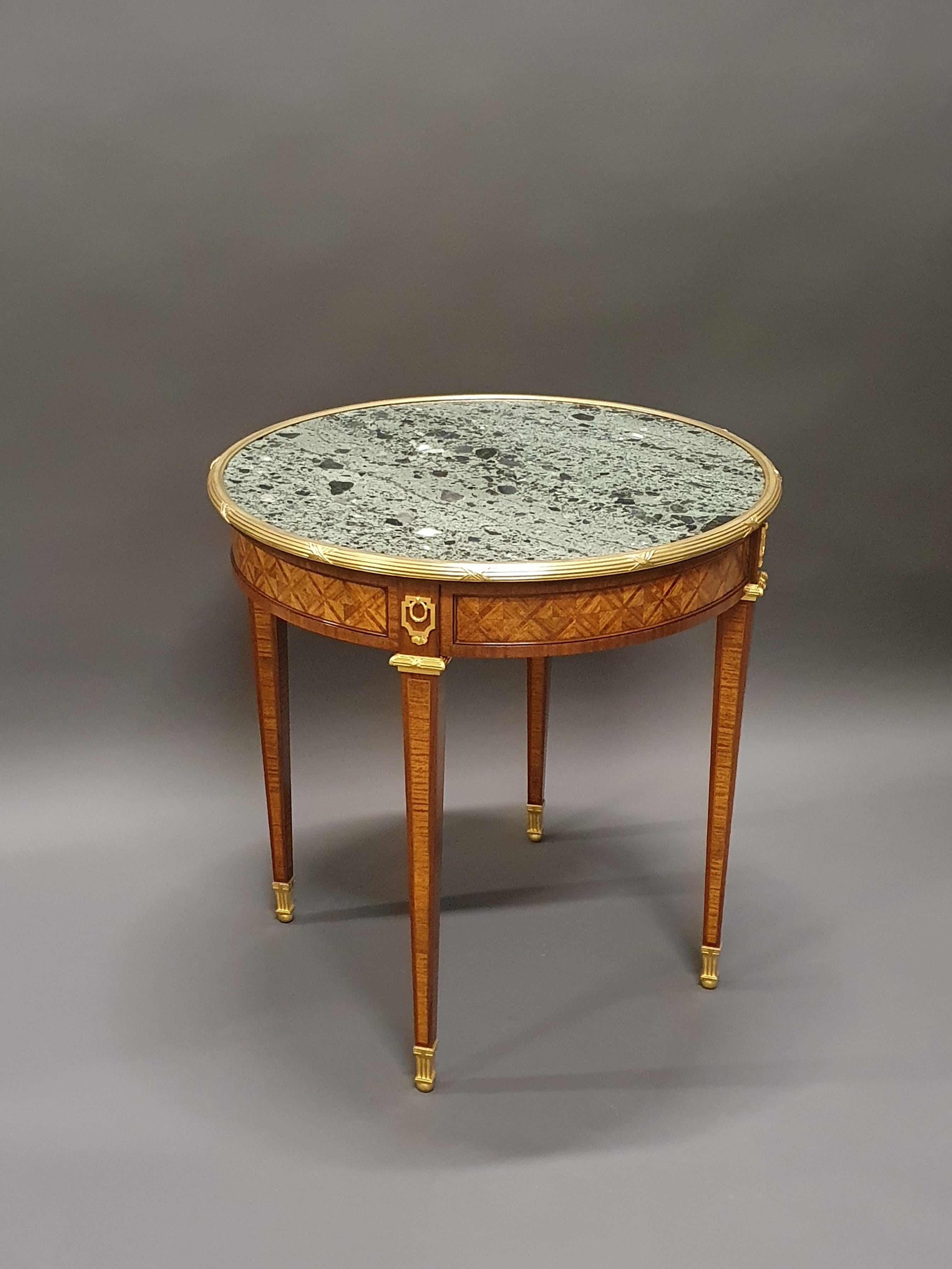 Large Louis XVI style gueridon table in kingwood marquetry with geometric shapes in mahogany frames.

Beautiful finely chiseled gilt bronze ornamentation.

Magnificent green breccia marble top.

Parisian work of good quality from the end of