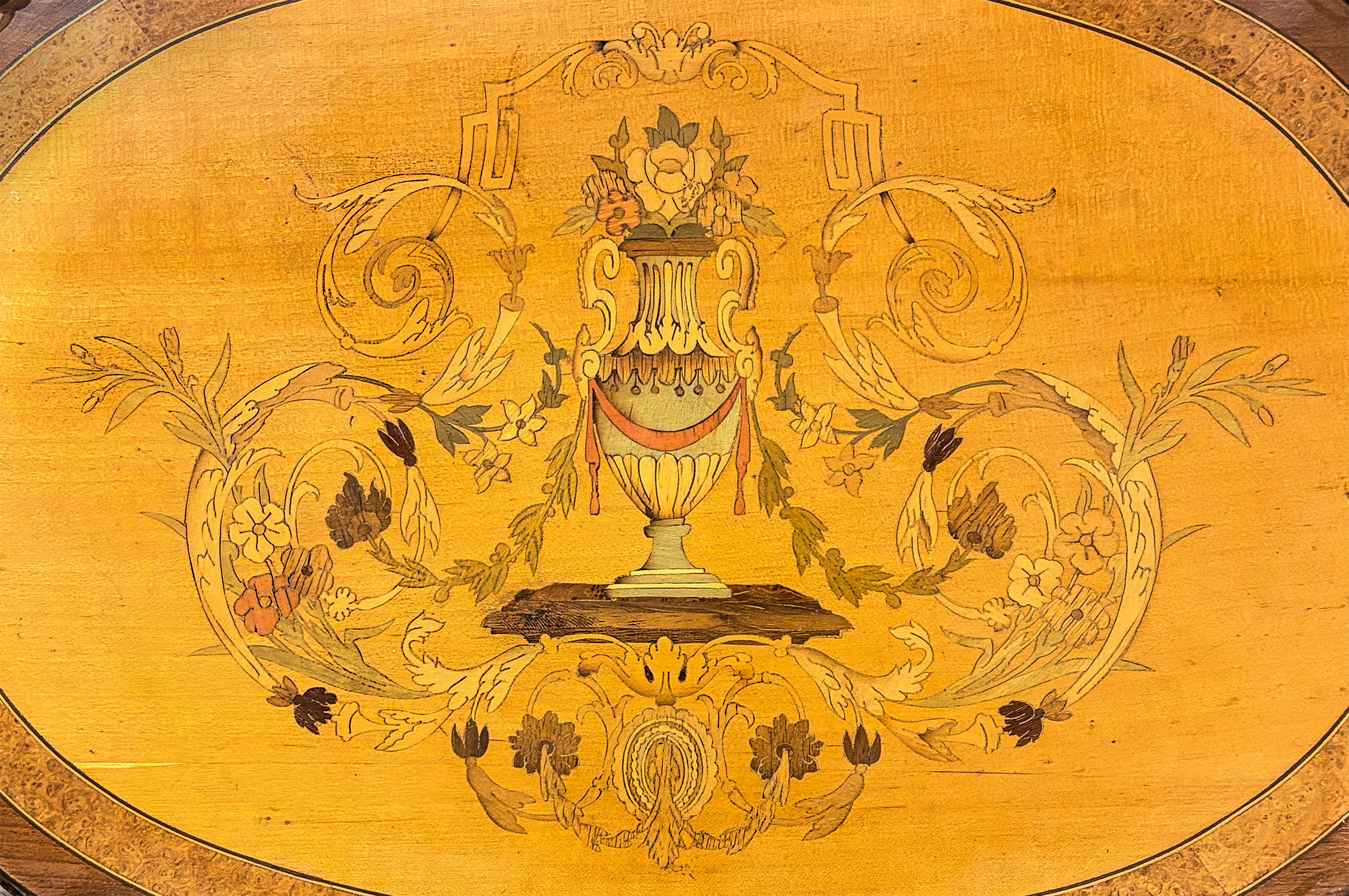 Une élégante table d'appoint à deux niveaux avec un plateau en marqueterie colorée. Fabriquée en France à la fin du XIXe siècle, cette petite table repose sur des pieds colonnes cannelés et des pieds pattes. La tablette inférieure est décorée de