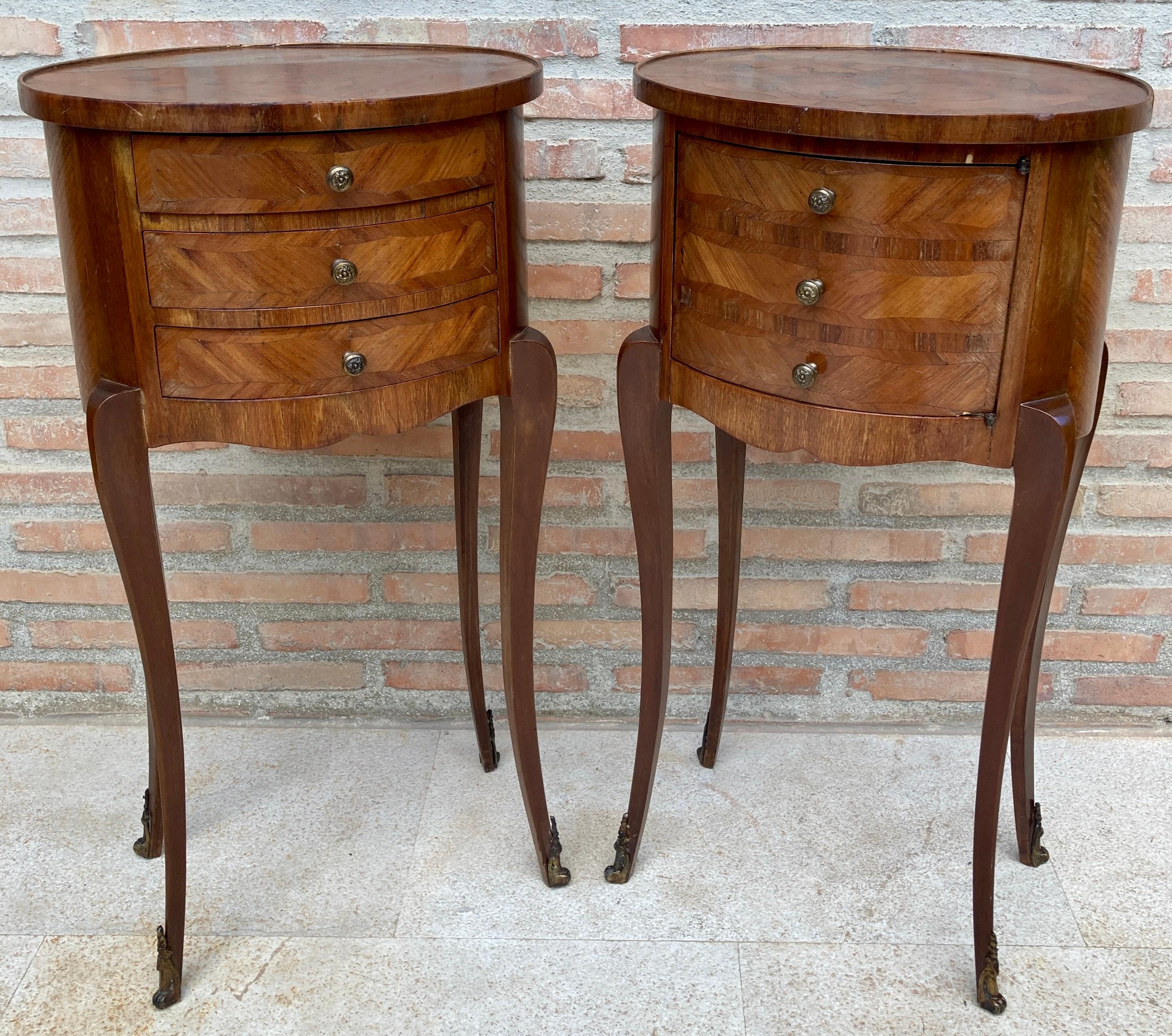 Two beautiful French, walnut side tables with Louis XVI style inlays made in the early 20th century. They are raised on four elegant feet topped with bronze decoration and one table has three front drawers with brass handles and the other a front