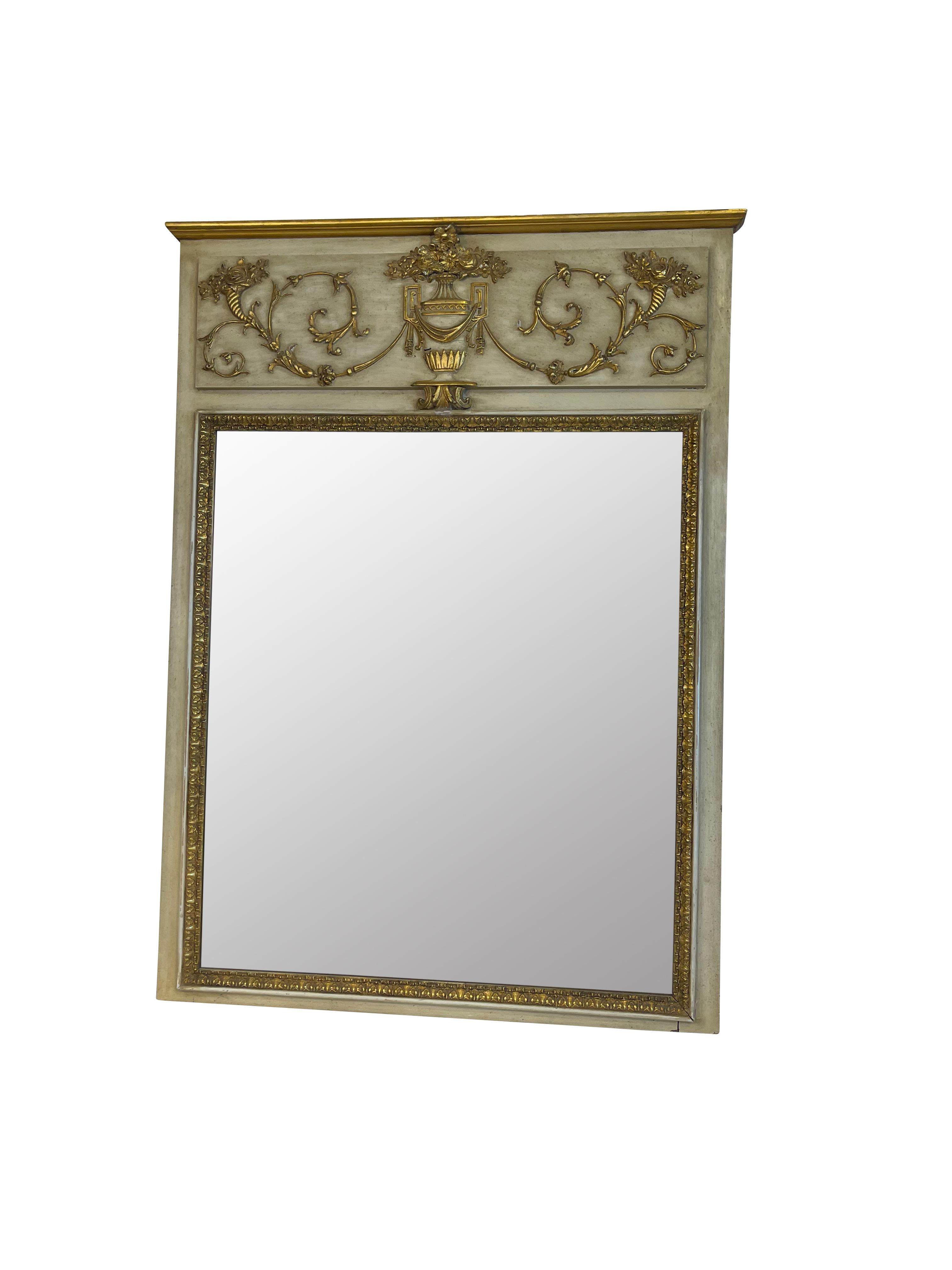 Lovely decorative ivory and gilt French Louis XVI style trumeau mirror with a classical gilt urn and foliate and floral decoration. Corners decorated cornucopia of flowers. Measures 53 X 38 X 1.75. Beautiful patina to gilding.
 